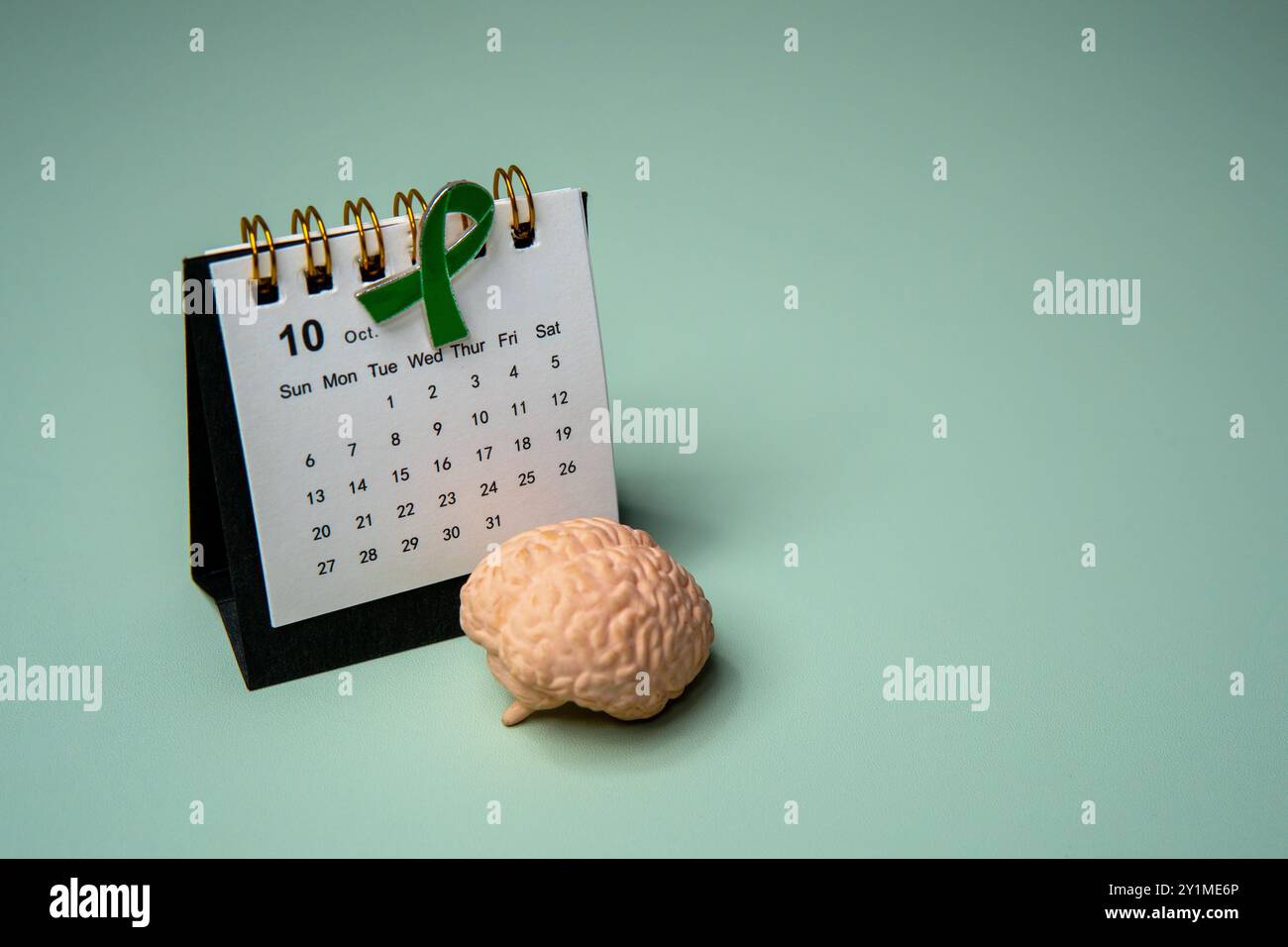 Ein Kalender öffnete sich bis Oktober und ein grünes Band, das das Bewusstsein für psychische Gesundheit symbolisiert. Kopierbereich für Text. Stockfoto