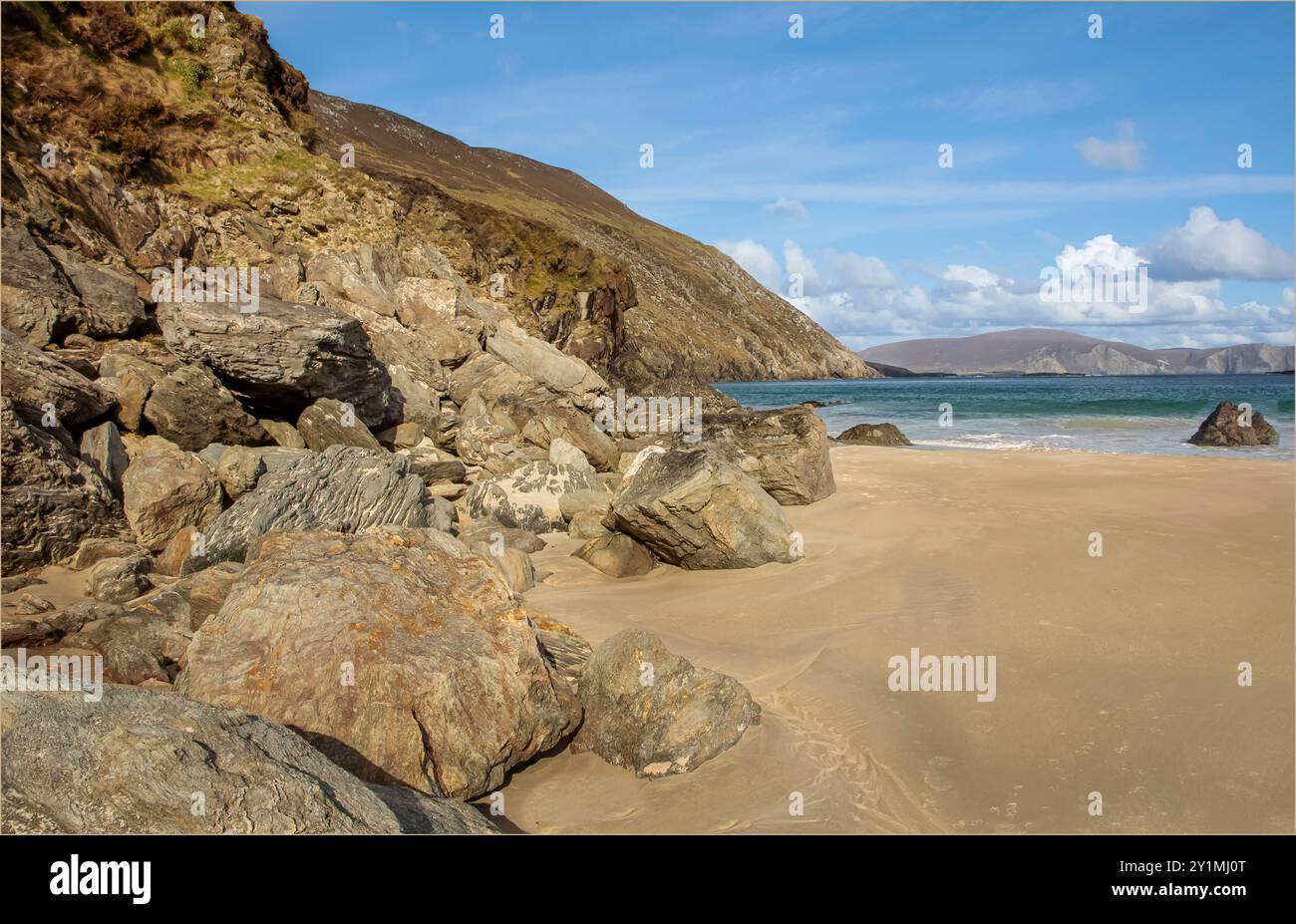 Achill Island, County Mayo, Irland - 26. April 2023 - Felsen fallen an einem Strand mit klarem Sand und Blick auf das Meer Stockfoto