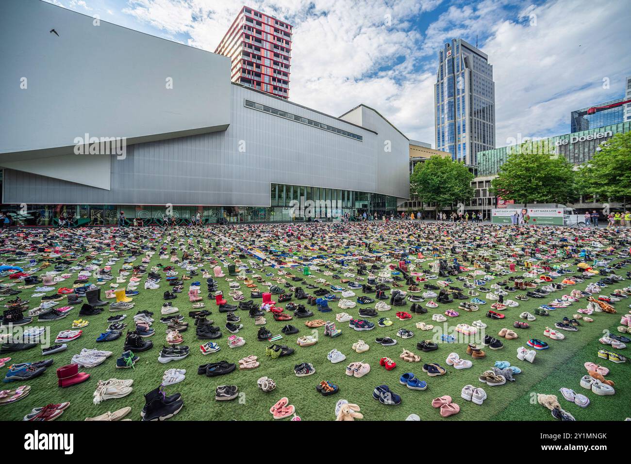 Schouwburgplein, mit 17.000 Schuhen in einer Gedenkveranstaltung, zum elften Monat Jahrestag der israelischen Militäraktion gegen Gaza. Der neunten Schuhprotest fand auf dem Schouwburgplein in Rotterdam statt. Mit bekannten und nicht so bekannten Sprechern nahm jeder die IT-Praktikantin mit, um einige der 17.000 Namen der Kinder, die bisher in Gaza getötet wurden, vorzulesen. Die Schuhe sollen gedenken und auch ein Ende des von Israel begangenen Völkermordkrieges gegen Gaza fordern. Dieser Krieg hat bereits Zehntausende von unschuldigen Palästinensern das Leben gefordert. Der heutige Gedenkprotest findet genau elf Monate seit Beginn statt Stockfoto