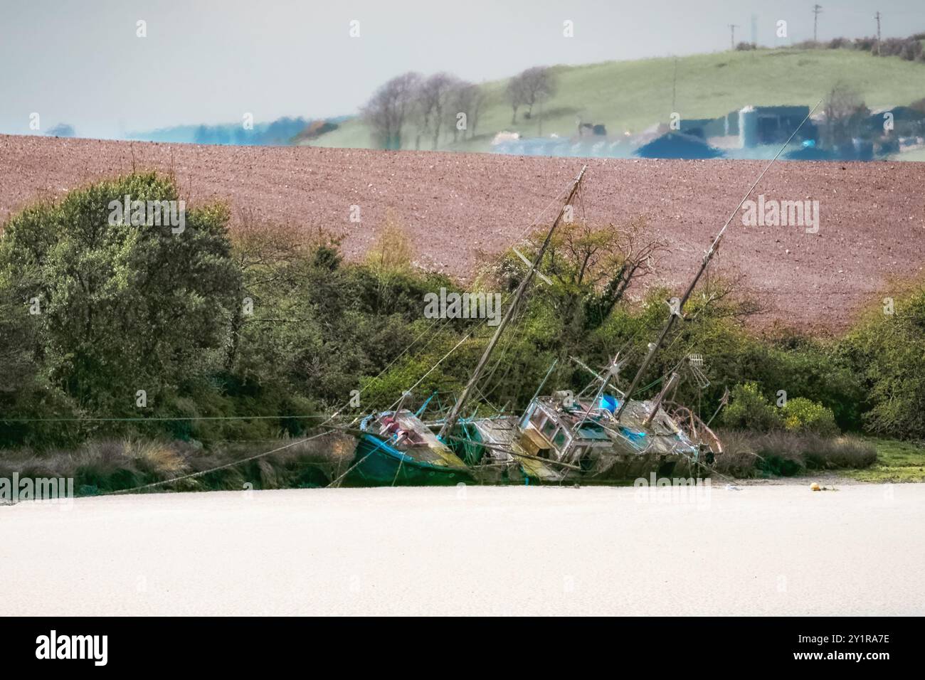 Das Boot liegt an einem Sandstrand. Die Boote sind aus Holz, verwittert und haben Masten, was darauf hindeutet, dass es sich um Segelschiffe handelt. Das Boot ist umgeben von Stockfoto