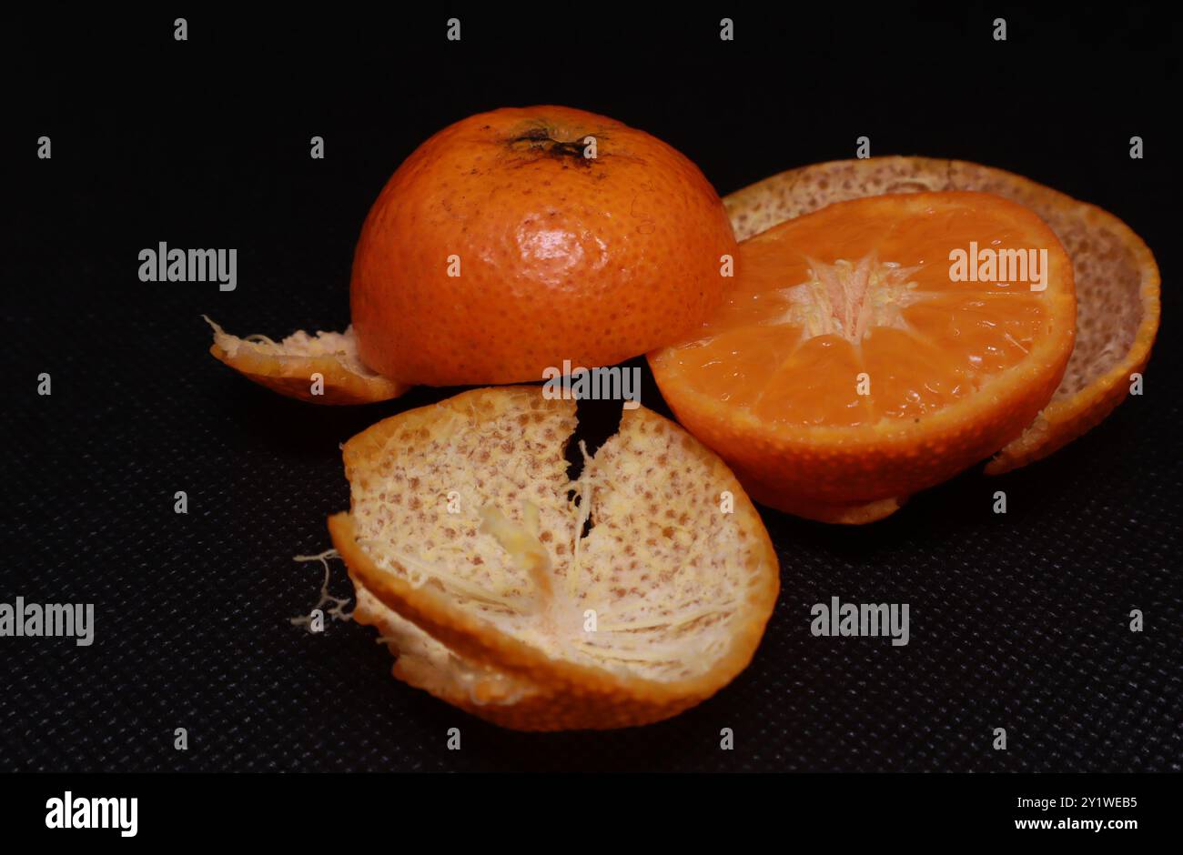 Frische sizilianische Orange, Mandarine mit grünen Blättern auf schwarzem Hintergrund. Stockfoto