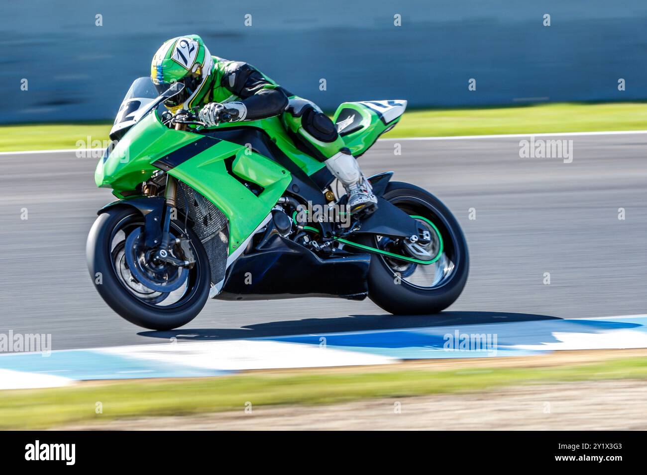 Aufregendes Bild eines grünen Motorrads, das auf einer Rennstrecke rasant fährt und den Nervenkitzel und Adrenalin eines professionellen Motorradrennens in Aktion zeigt. Alle l Stockfoto