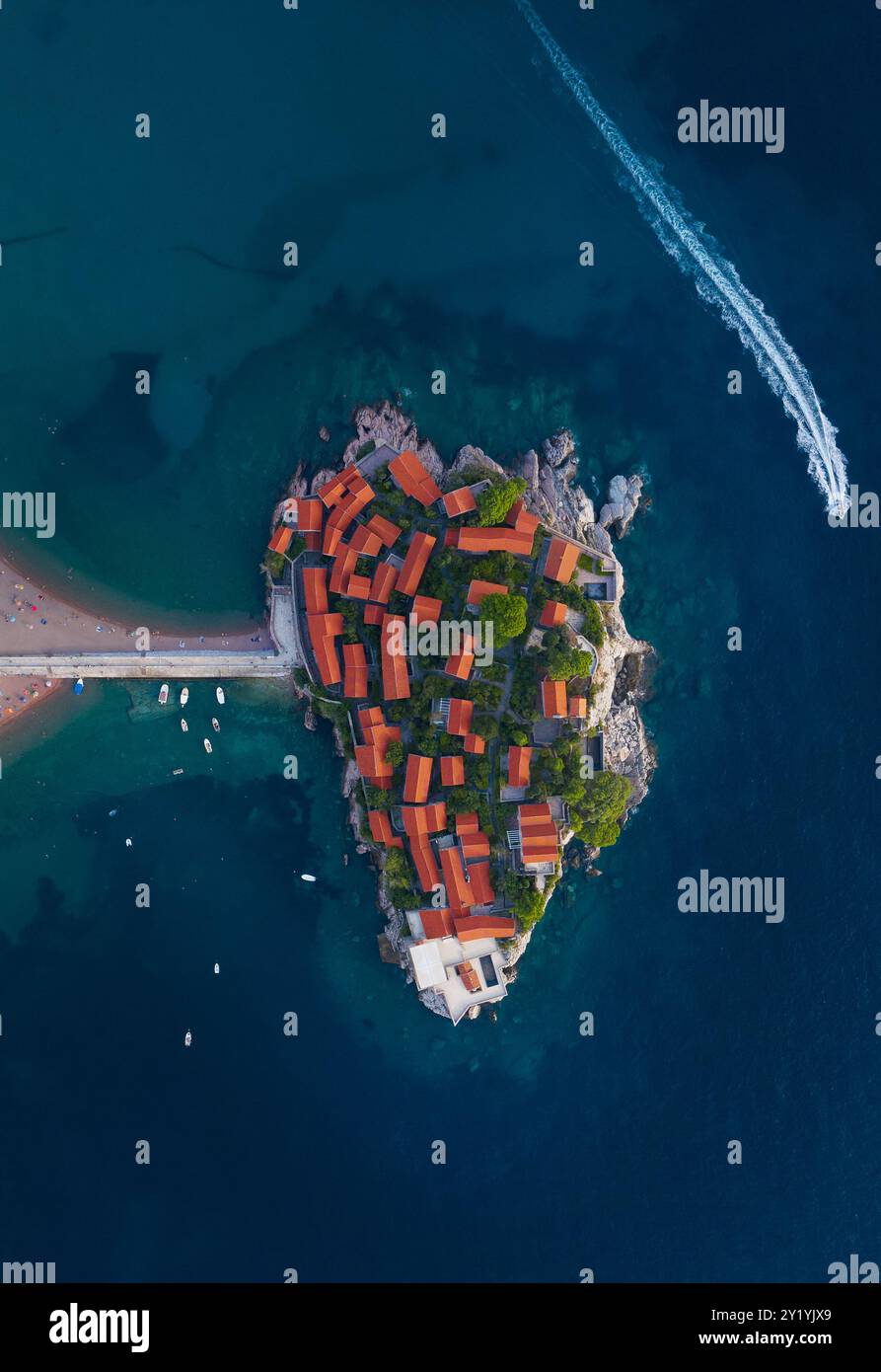 Atemberaubende Aussicht aus der Vogelperspektive auf die malerische Insel Sveti Stefan in Montenegro mit ihren berühmten Gebäuden mit roten Dächern, umgeben von türkisfarbenem Wasser. Szene Stockfoto