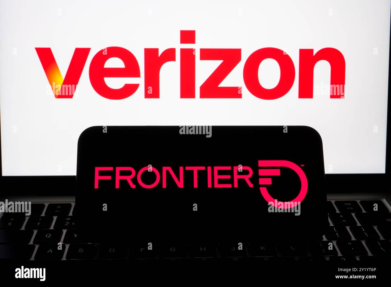 Verizon- und Frontier Communications-Logos auf Bildschirmgeräten, die Markenzeichen und Partnerschaft im Telekommunikationsbereich betonen. Stafford, Vereinigtes Königreich Stockfoto