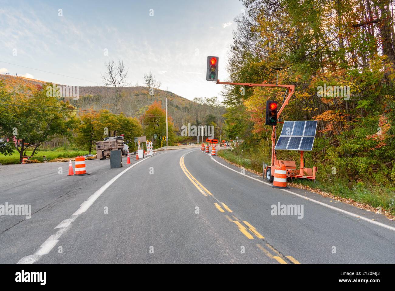 Signale, die von Solarpaneelen auf rot am Anfang einer Baustelle auf einer Bergstraße bei Sonnenuntergang im Herbst betrieben werden Stockfoto