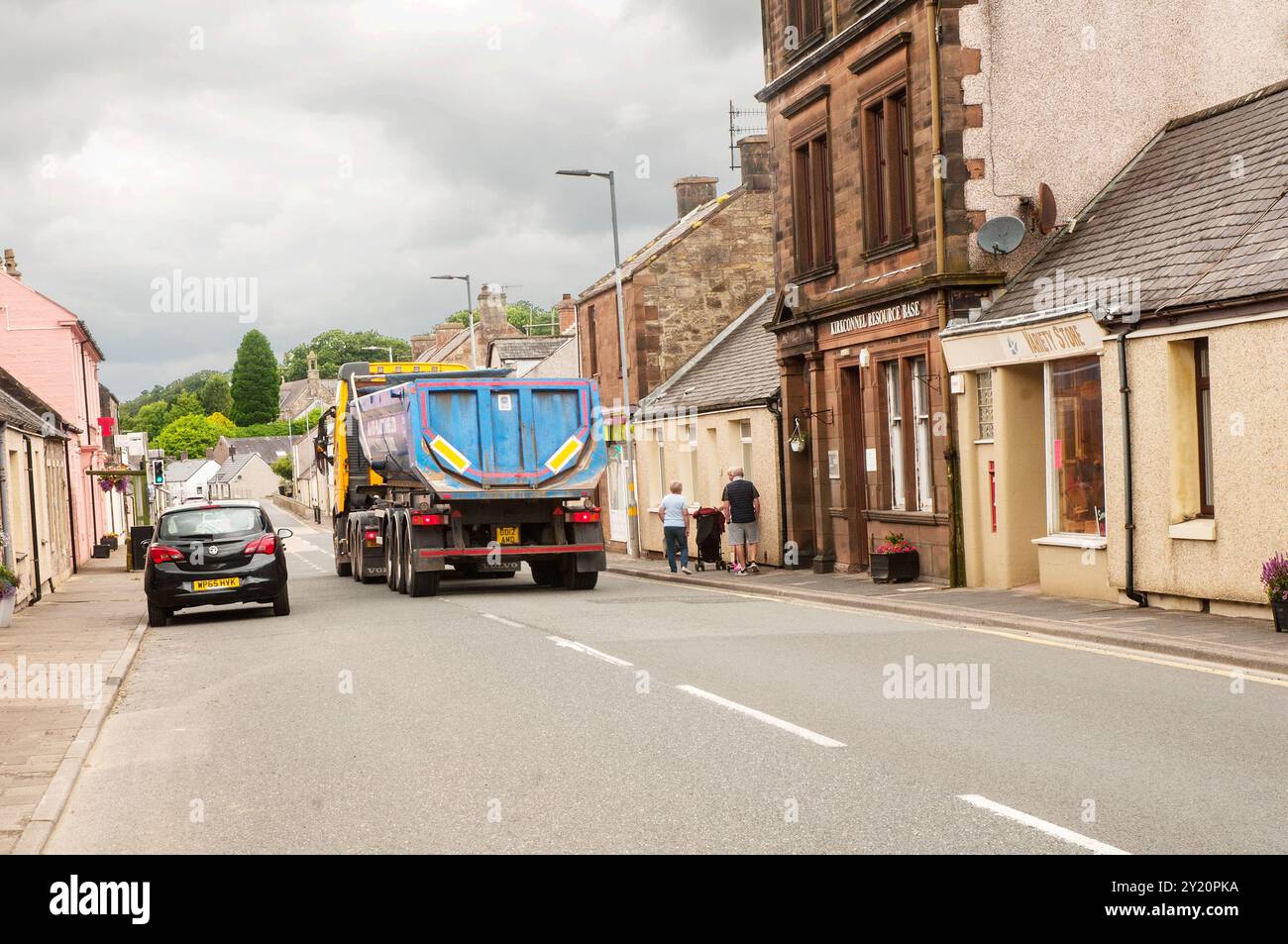 Menschen stehen auf Fußwegen, während ein großer Lastwagen durch das Dorf Kirkconnel in Dumfries und Galloway Schottland fährt Stockfoto