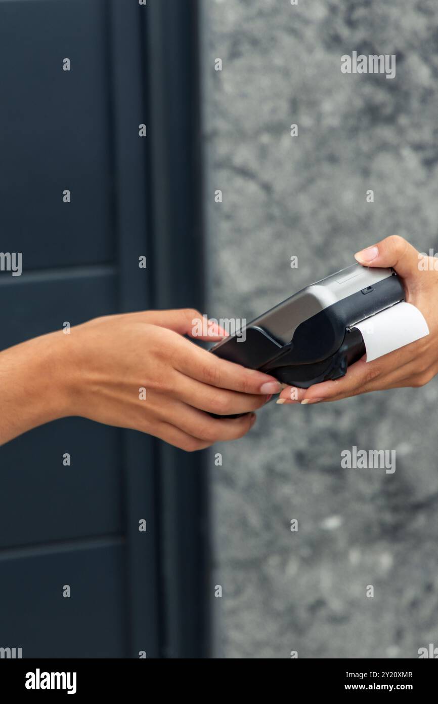 Nahansicht einer Hand, die eine PIN an einem von einem Anbieter bereitgestellten Zahlungsterminal eingibt, um für einen Kauf zu bezahlen. Das Bild konzentriert sich auf den Zahlungsprozess Stockfoto