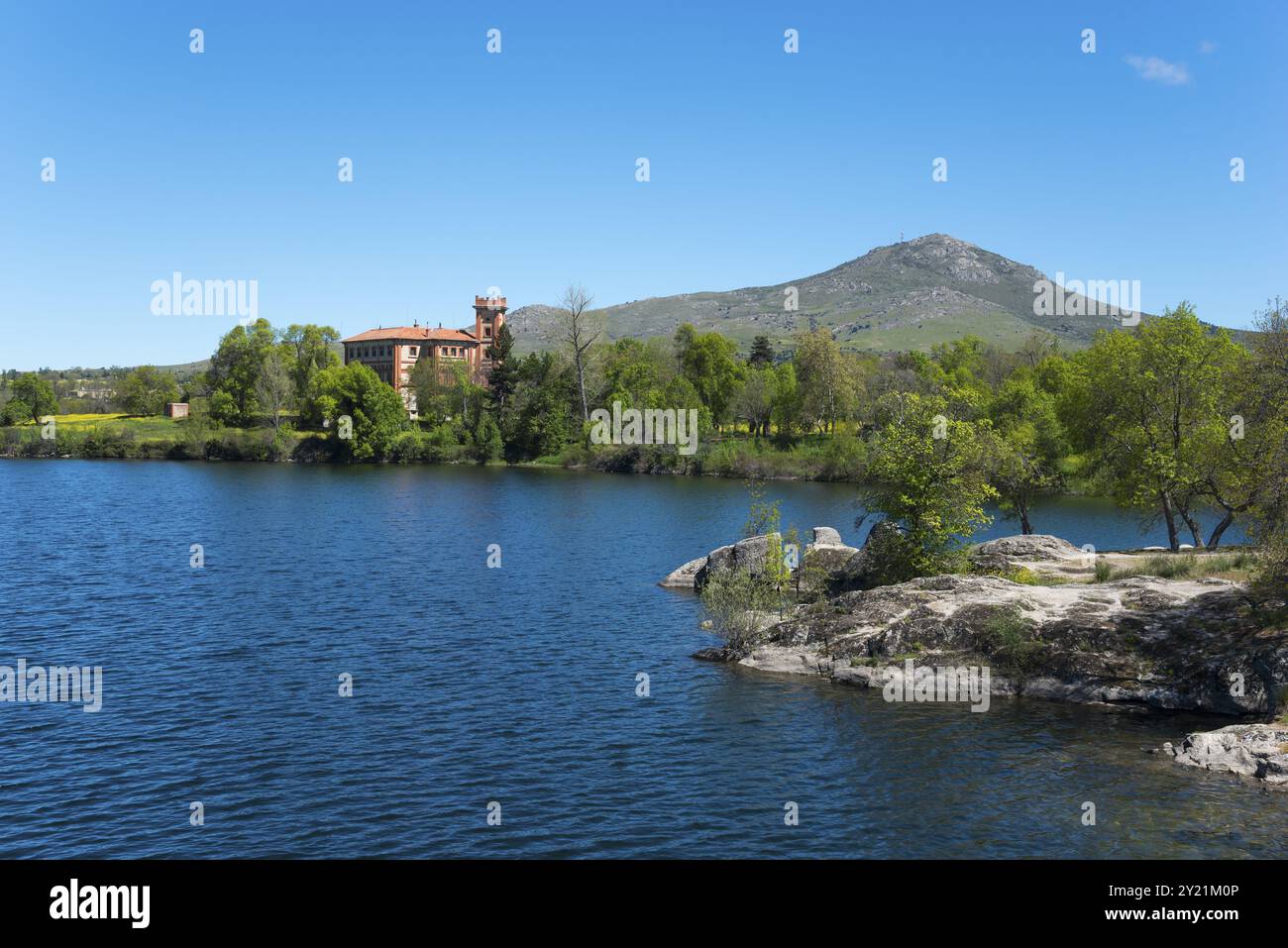 Klarer See neben einem Gebäude, umgeben von Natur und Bergen unter blauem Himmel, Palast, Palacio de Santa Cecilia, Embalse de Ponton, Ponton Reser Stockfoto