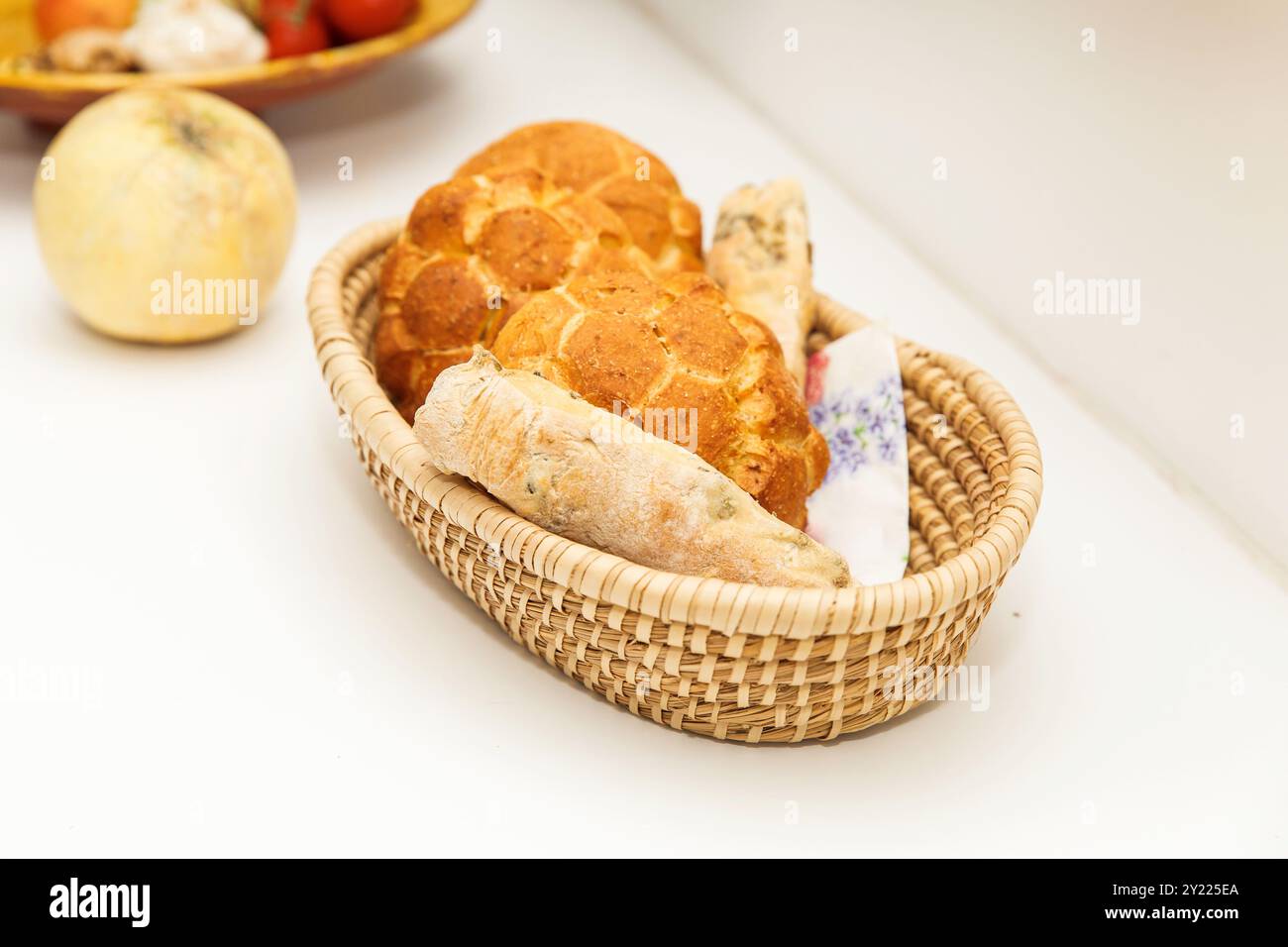 Verschiedene Brotlaibe in einem Korb auf einem weißen Tisch, frisch gebackene, traditionelle Backwaren, eine Vielzahl von Weizen- und Roggenbroten im Webkorb, bre Stockfoto