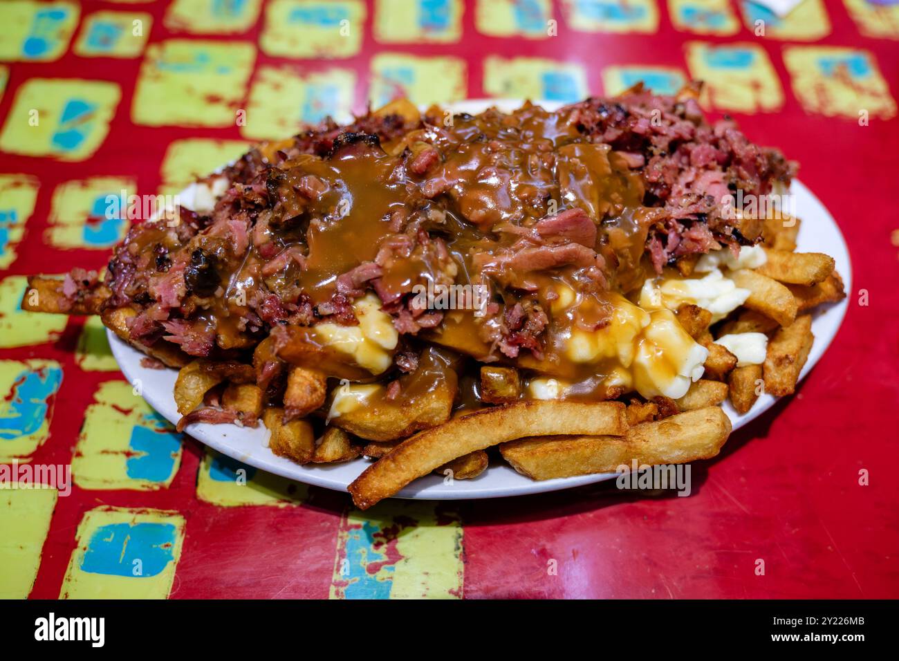 Montreal Fleischpoutine serviert mit Pommes frites, Käsequark und brauner Soße im Fast Food Restaurant La Banquise in Montreal, Quebec, Kanada Stockfoto