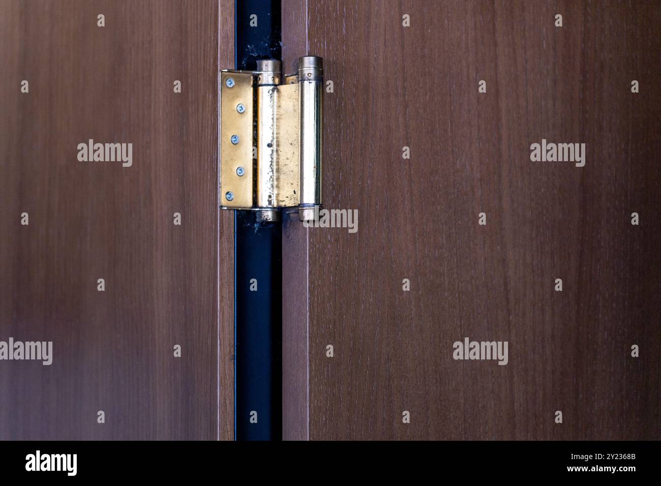 Metallscharnier an einer offenen Tür: Hölzerner Hintergrund und Minimalismus im negativen Raum. Stockfoto