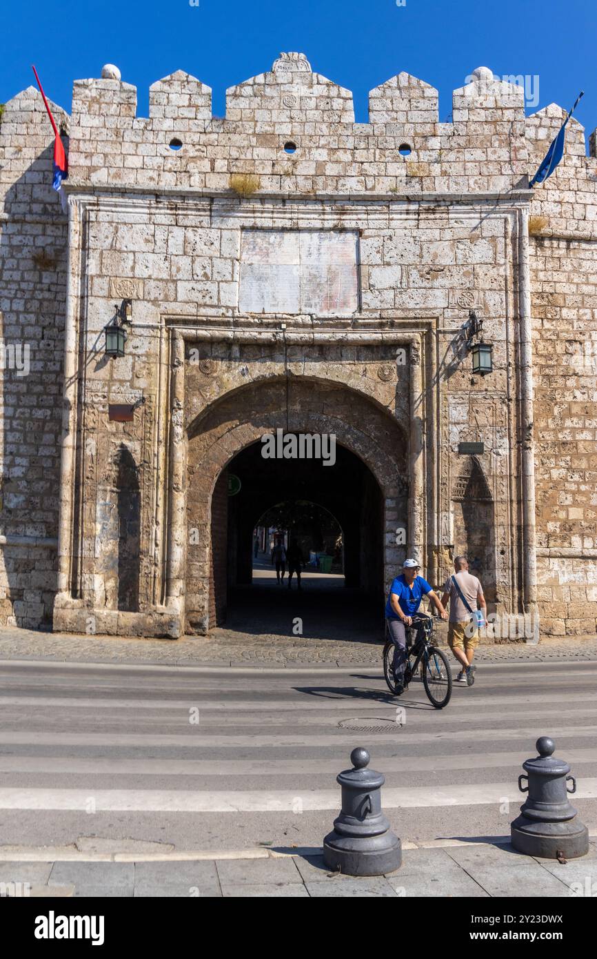 Ein Radfahrer und ein Fußgänger am Stambol-Tor - dem Haupteingang zur Festung NIS in Serbien an einem schönen sonnigen Sommertag mit blauem Himmel. Stockfoto