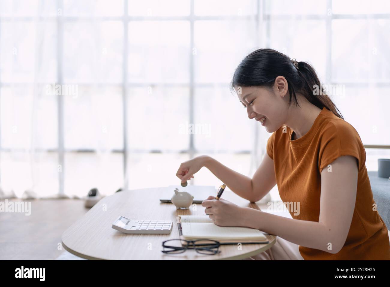 Eine Frau plant finanzielle Sparpläne in einem Notizbuch, organisiert ihre Ziele und Budgetstrategien, um langfristige finanzielle Stabilität und Erfolg zu erreichen. Stockfoto