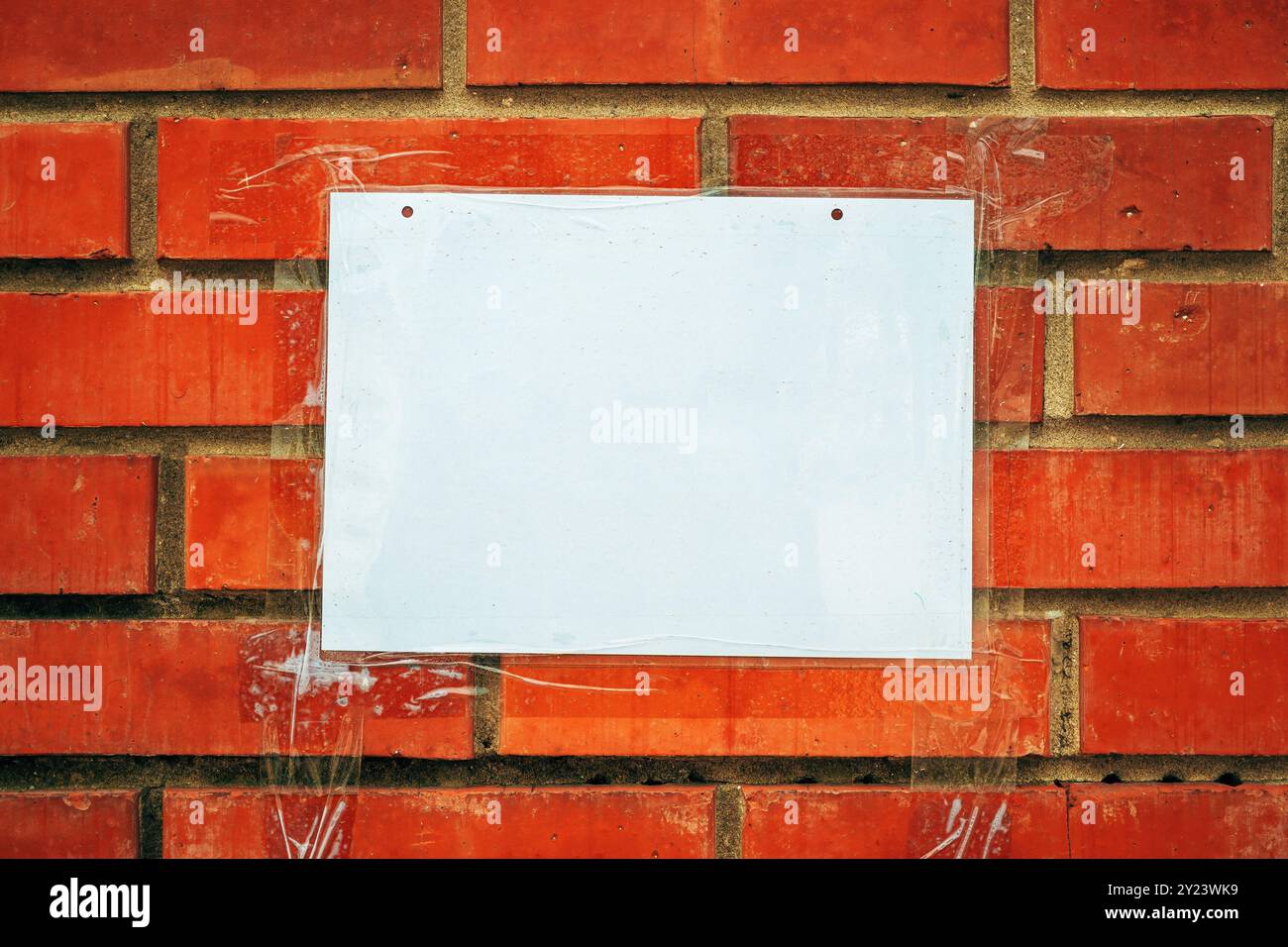 Leeres weißes Notizpapier auf dem Hintergrund der Ziegelwand Stockfoto