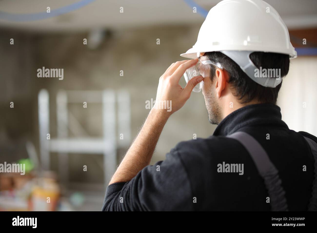 Rückansicht eines Bauarbeiters mit Schutzbrille in einem Haus, das sich in der Reform befindet Stockfoto