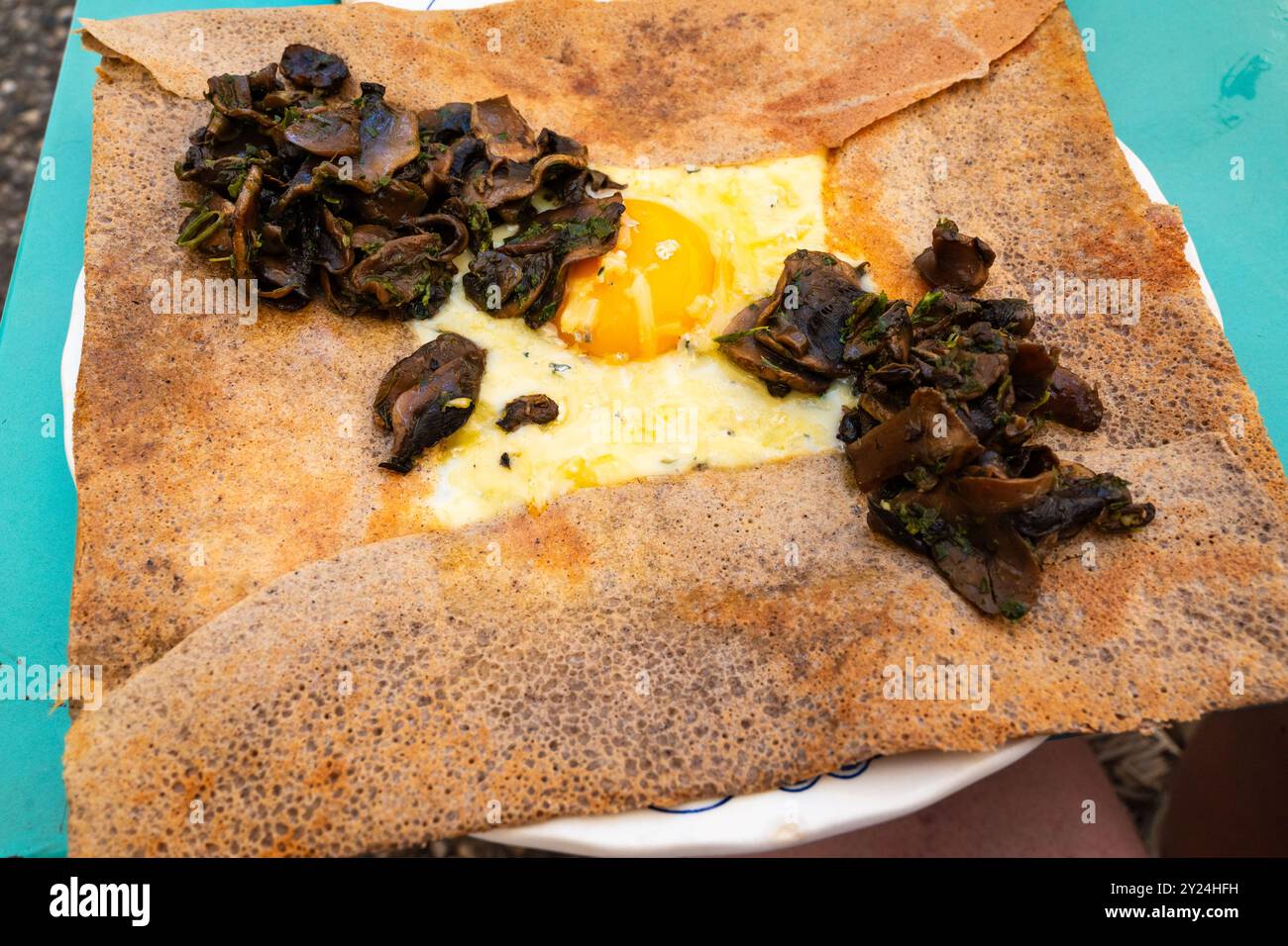 Herzhafte Galette (französischer Pfannkuchen mit Buchweizenmehl) mit gebratenen Pilzen, Ei und Käse, serviert zum Mittagessen in einem französischen Bistro Stockfoto