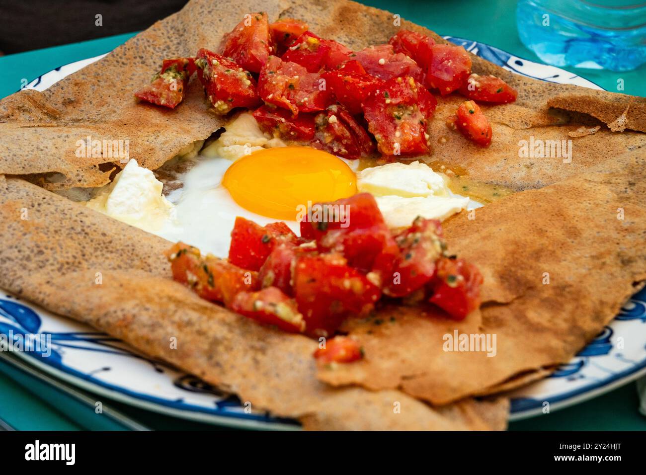 Herzhafte Galette (französischer Pfannkuchen mit Buchweizenmehl) mit Tomaten, Ei und Käse, serviert zum Mittagessen in einem französischen Bistro Stockfoto