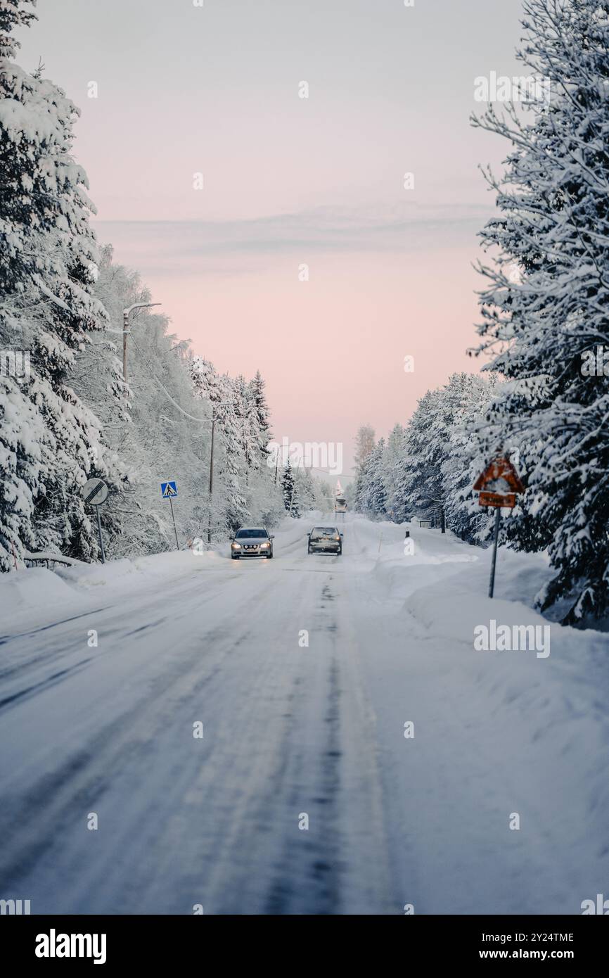 Autos fahren zum Santa Claus' Village entlang der verschneiten Straße in Rovaniemi, Lappland Stockfoto