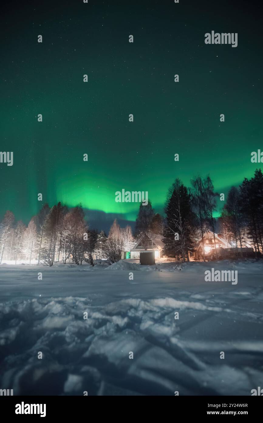 Kräftig grüne aurora Borealis über Haus in verschneiten Wäldern in Rovaniemi, Lappland Stockfoto