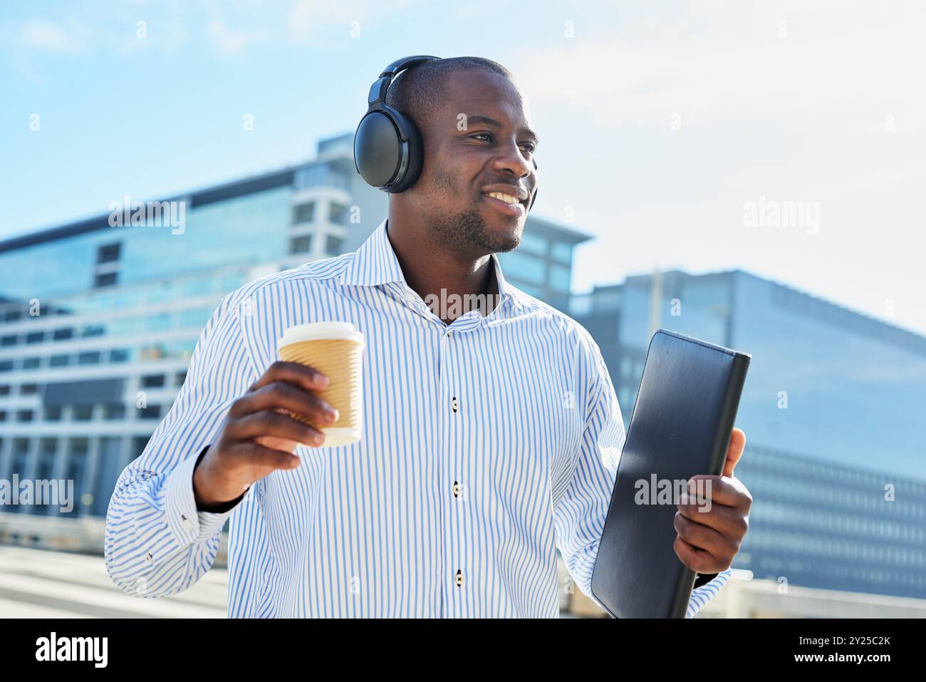 Selbstbewusster Geschäftsmann, der Kaffee und Musik in urbaner Umgebung genießt Stockfoto