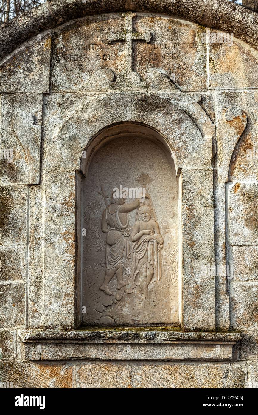 Steinnische mit einem Kreuz und einem Basrelief, das die Taufe Jesu durch Johannes den Täufer darstellt. Bisegna, Provinz L'Aquila, Abruzzen, Italien, Europa Stockfoto