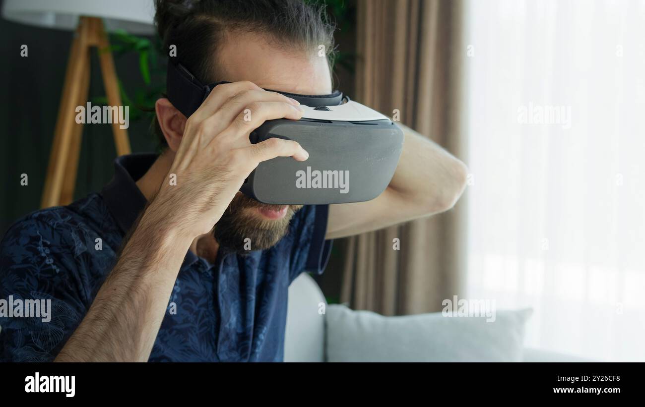 Ein junger Mann mit einem VR-Headset erkundet die Virtual-Reality-Erfahrung. Interaktion mit der virtuellen Umgebung Stockfoto