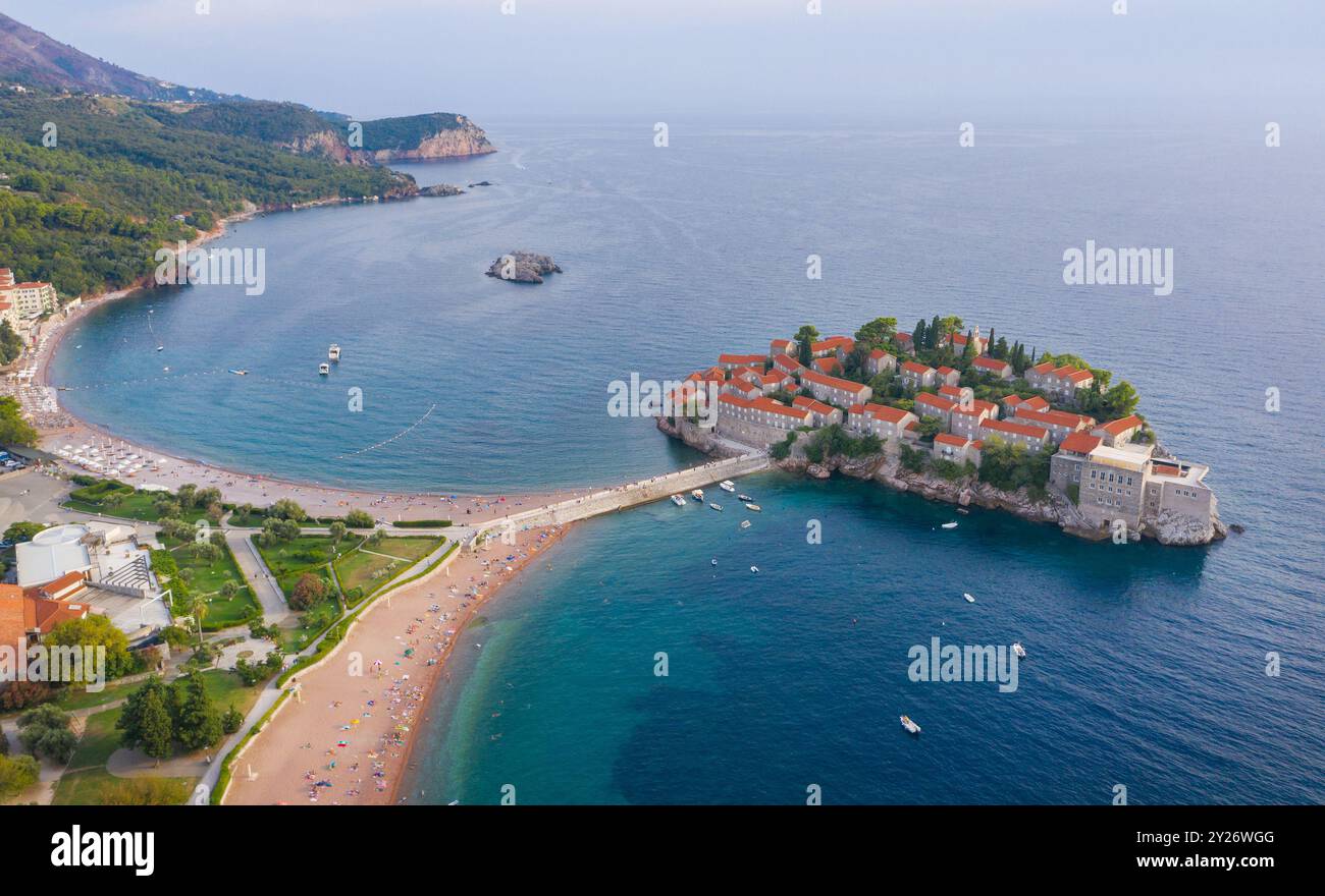 Atemberaubende Aussicht aus der Vogelperspektive auf die malerische Insel Sveti Stefan in Montenegro mit ihren berühmten Gebäuden mit roten Dächern, umgeben von türkisfarbenem Wasser. Szene Stockfoto