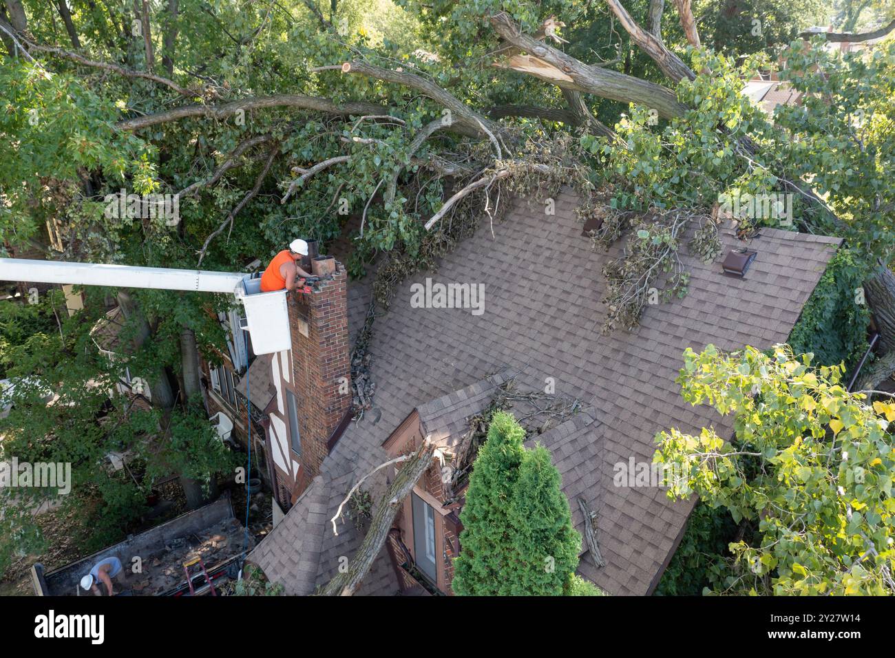 Detroit, Michigan - Ein Arbeiter zerlegt einen gemauerten Kamin, nachdem ein Sturm mit 70 km/h Windböen einen 15 Tonnen schweren, 110 Meter hohen Baumwollwald niedergeblasen hat. Der Baum ist gerissen Stockfoto