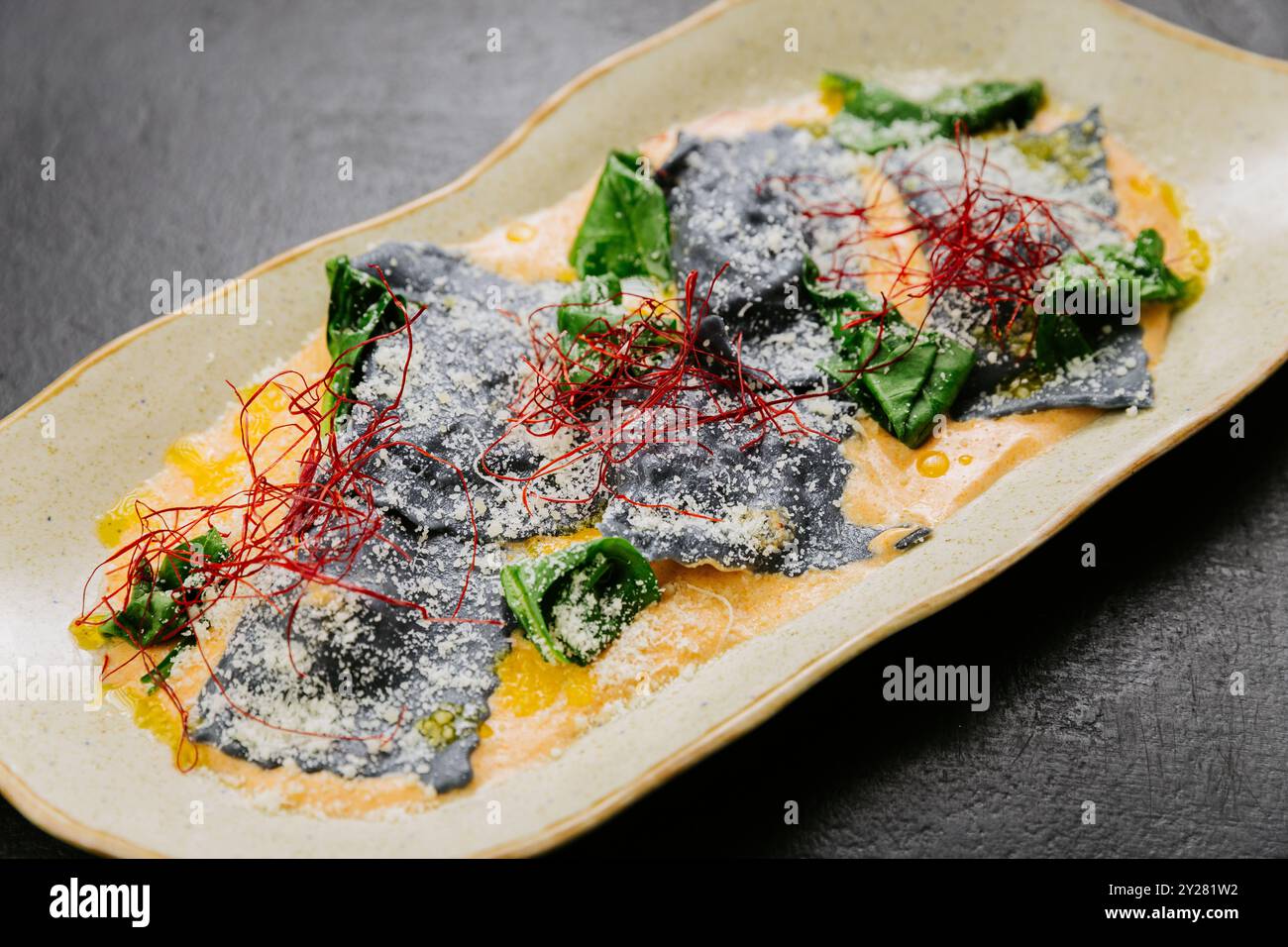 Gourmet-Tintenfisch-Ravioli mit lebhaften Garnituren in einer cremigen Sauce - ein elegantes und künstlerisches Gericht Stockfoto