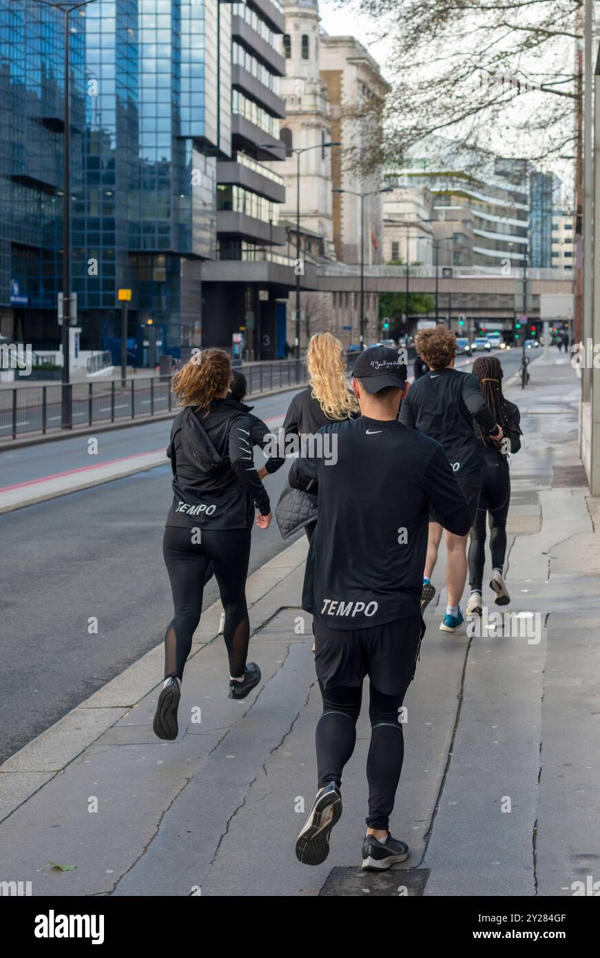 Gemischte Gruppe von Läufern am Sonntagmorgen oder Joggern in schwarzen Outfits, die in der Lower Thames Street in London, England, Großbritannien, laufen oder joggen Stockfoto