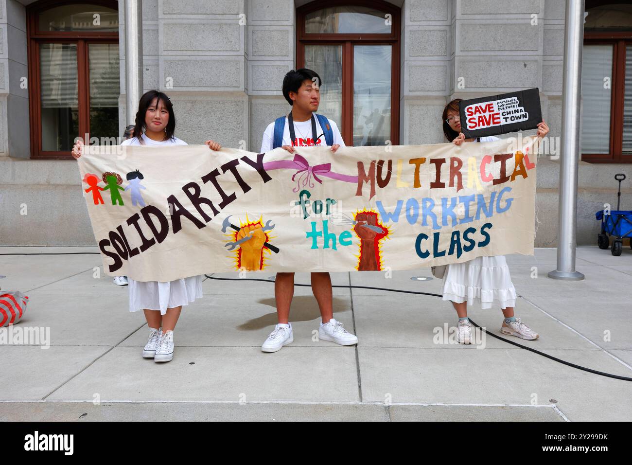 7. September 2024 In Philadelphia. Keine Arena in Chinatown Rallye und protestmarsch. Junge Menschen halten vor dem Rathaus ein Banner "Solidarität für die multirassische Arbeiterklasse". Die geplante Arena auf der Market St und N 11th St, befürchten die Gegner, wird die Gentrifizierung anregen, was zur Zerstörung und Zerstreuung der Chinatown-Gemeinschaft führen wird. Organisiert von der Save Chinatown Coalition Gruppe asiatisch-amerikanischer Gruppen und Verbündeter, begannen die verschiedenen Aktivisten ihre Kundgebung im Rathaus, bevor sie entlang der Market Street marschierten, vorbei an der geplanten Arena und in Chinatown endeten. Stockfoto