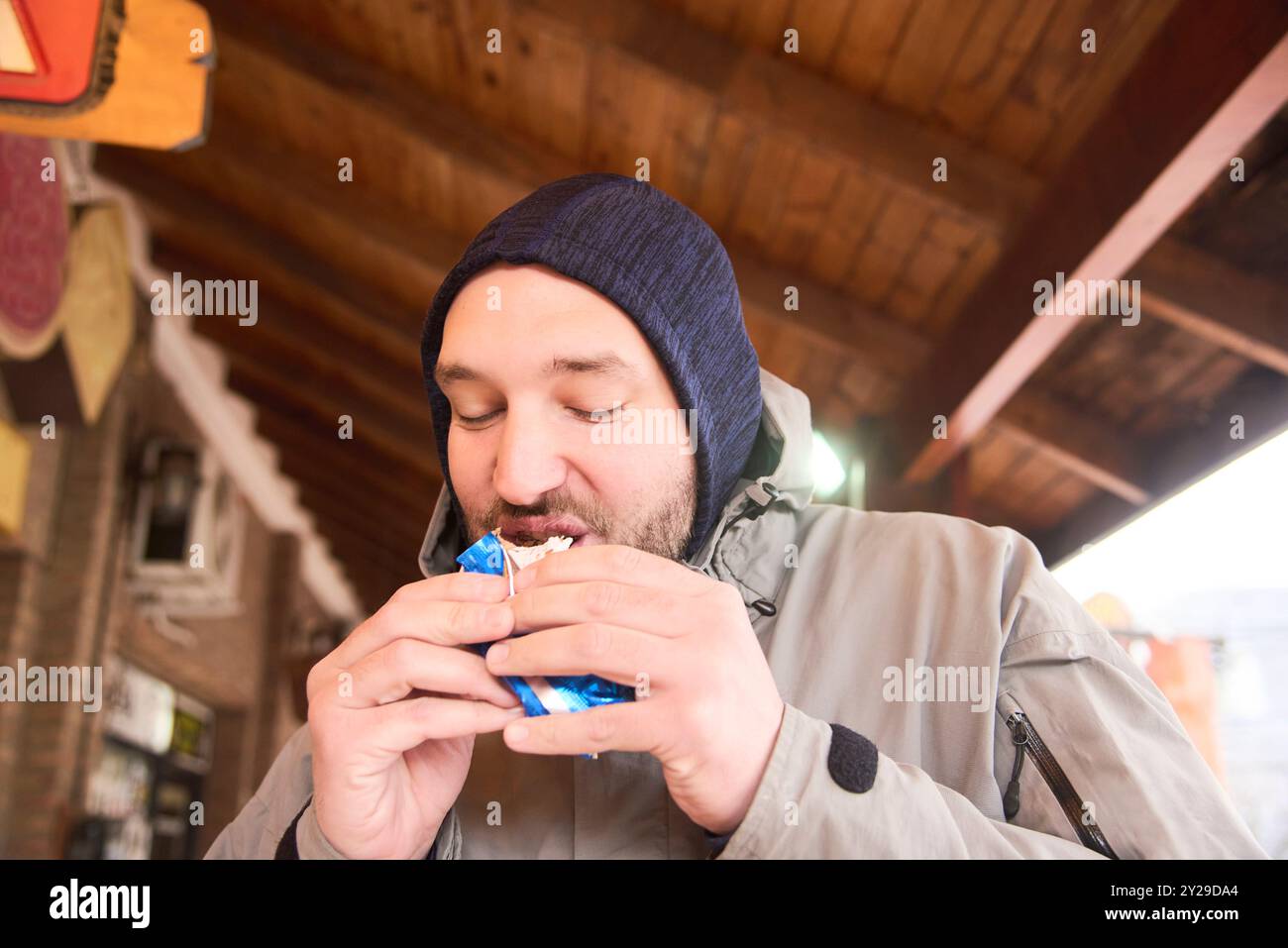 Nahaufnahme Porträt eines glücklichen jungen Mannes, der ein traditionelles Alfajor in Villa General Belgrano, Cordoba, Argentinien genießt. Stockfoto