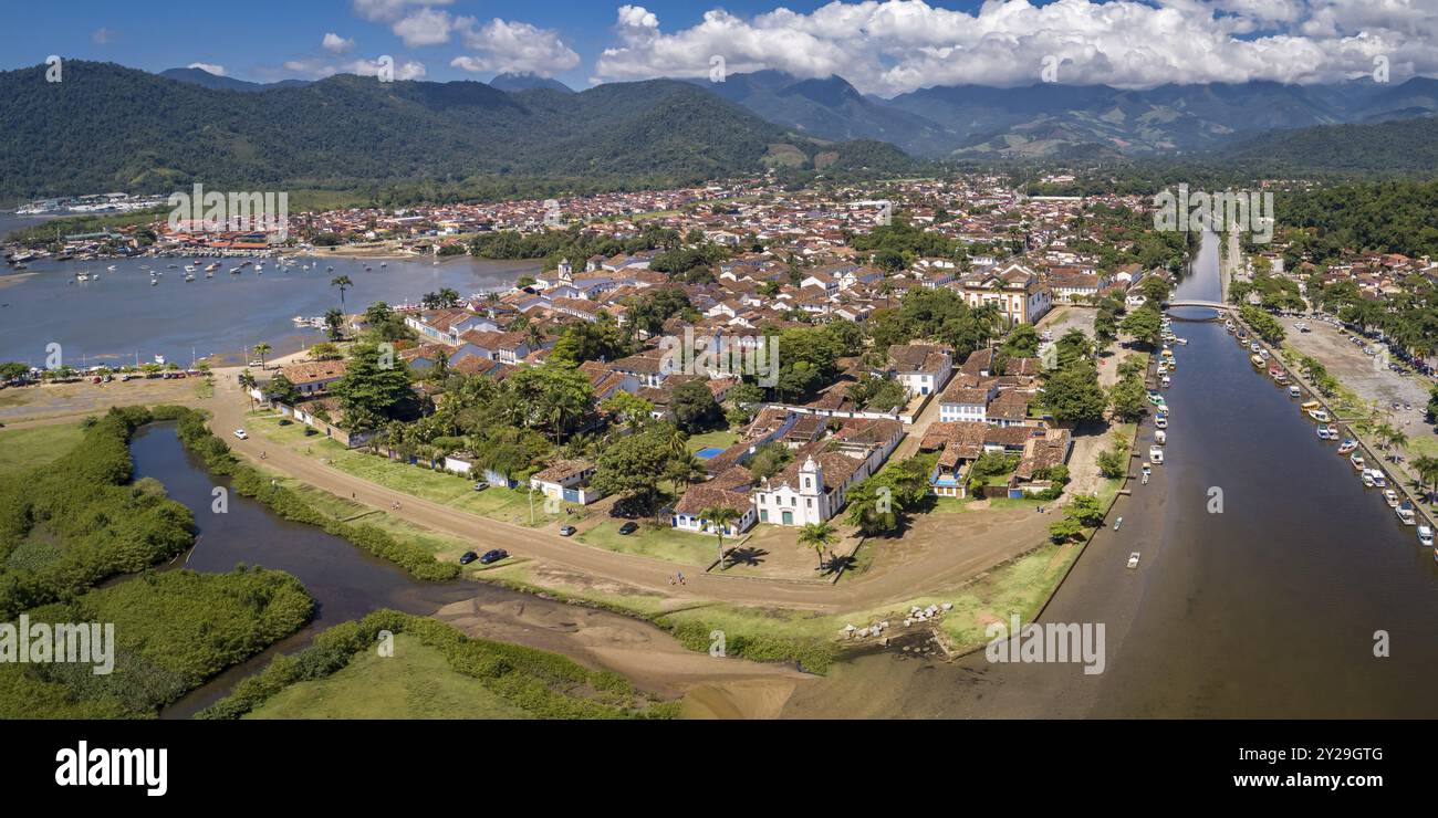 Blick aus der Vogelperspektive auf die historische Stadt Paraty mit Gezeitenfluss und grünen Bergen im Hintergrund, sonnigen Himmel mit weißen Wolken, Brasilien, UNESCO-Weltkulturerbe, so Stockfoto