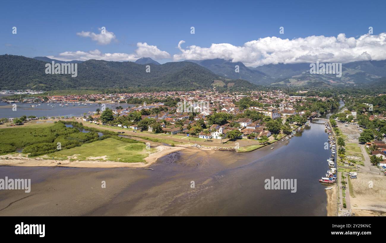 Blick aus der Vogelperspektive auf die historische Stadt Paraty mit Gezeitenfluss und grünen Bergen im Hintergrund, sonnigen Himmel mit weißen Wolken, Brasilien, UNESCO-Weltkulturerbe, so Stockfoto