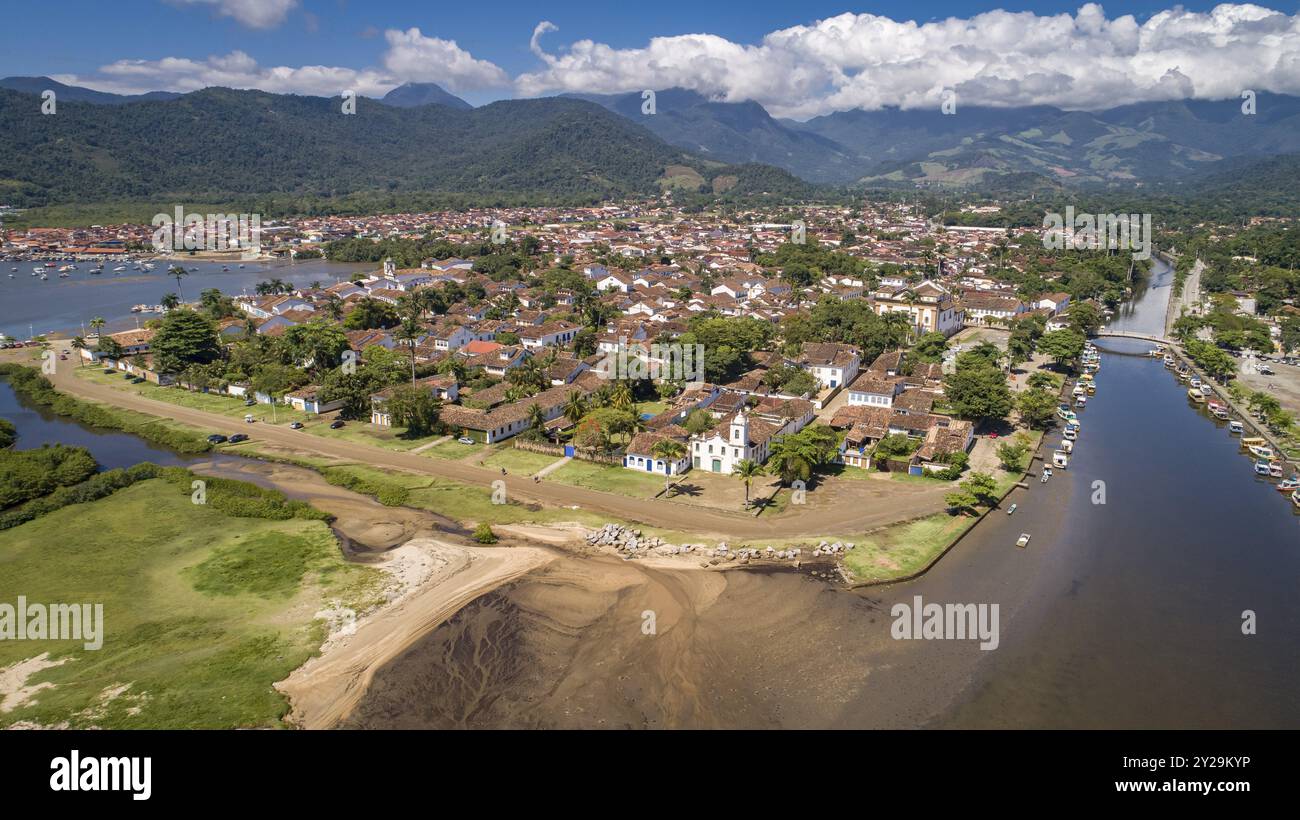 Blick aus der Vogelperspektive auf die historische Stadt Paraty mit Gezeitenfluss und grünen Bergen im Hintergrund, sonnigen Himmel mit weißen Wolken, Brasilien, UNESCO-Weltkulturerbe, so Stockfoto
