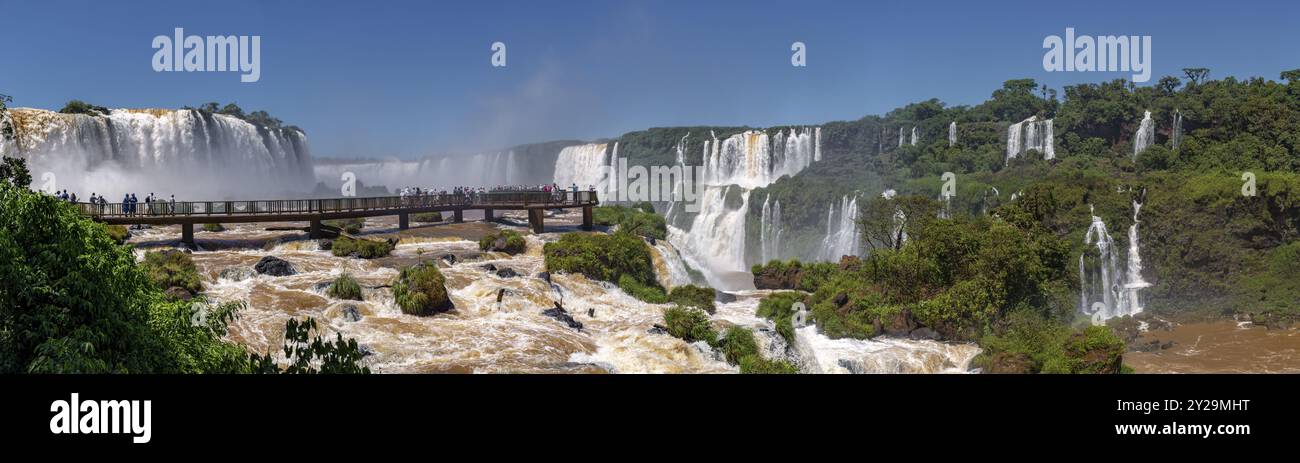 Panorama der spektakulären Iguazu-Fälle mit Besucherplattform und blauem Himmel Stockfoto