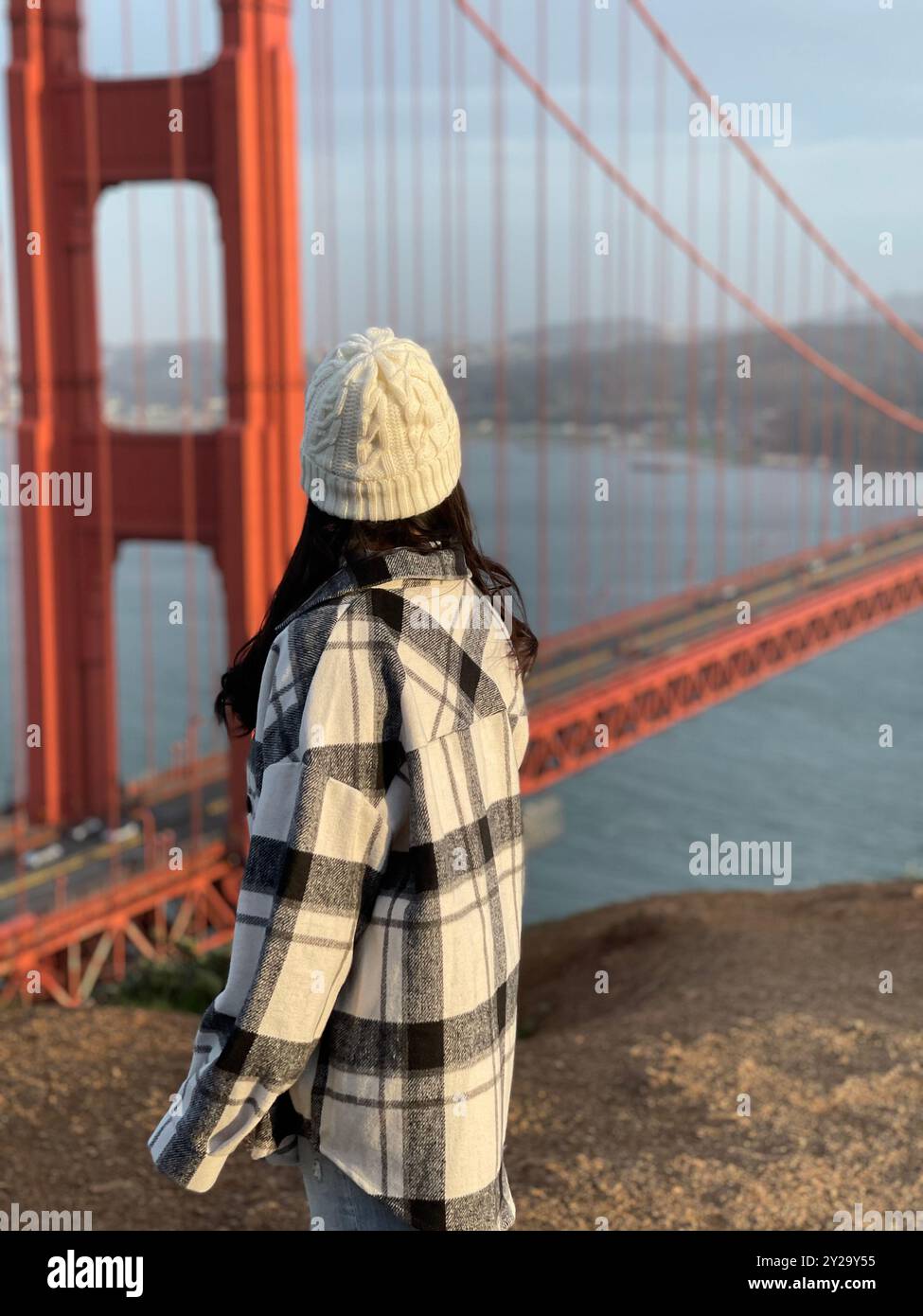 Mädchen mit Beanie, die an sonnigen Tagen die Golden Gate Bridge vom Vista Point in San Francisco, Kalifornien, ansieht Stockfoto