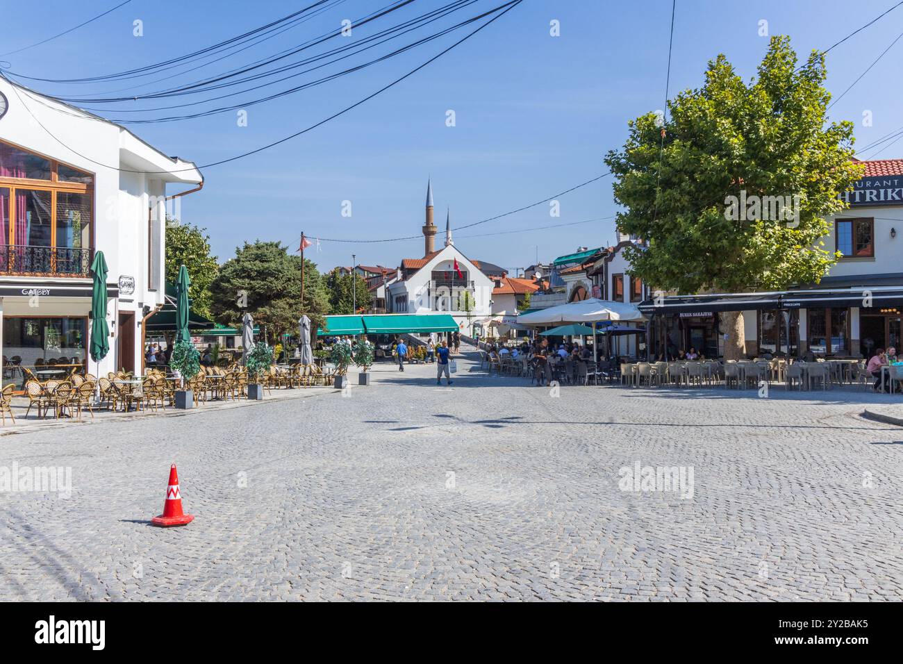 Die Leute saßen an einem sonnigen Sommertag vor Restaurants, Bars und Cafés im Stadtzentrum von Prizren im Kosovo, mit Tischen und Stühlen auf der Straße. Stockfoto