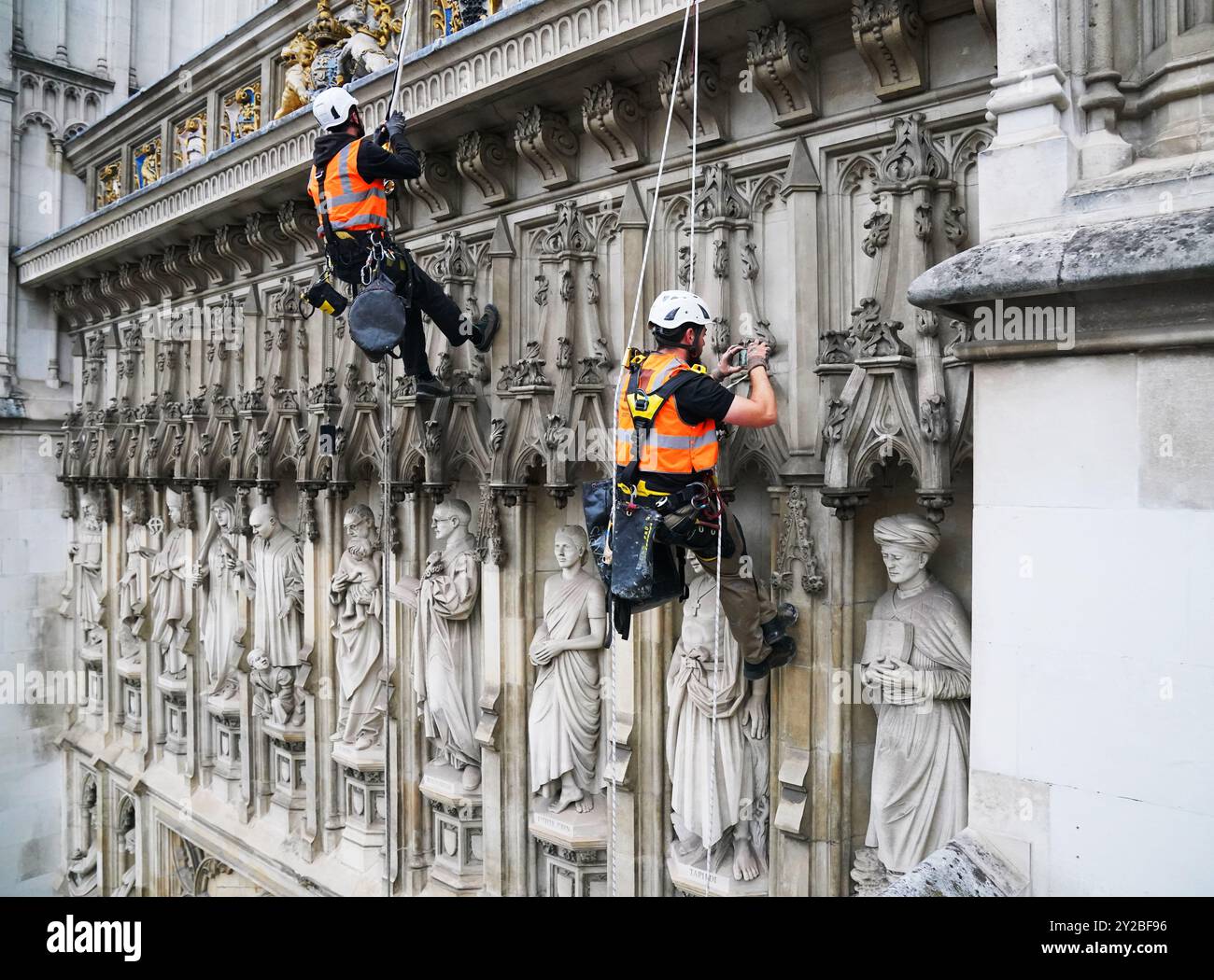 Die Abseilspezialisten Mike Hammond (rechts) und Oscar Banyard (links) führen eine Vermessung der West Towers in der Westminster Abbey im Zentrum von London durch. Der Zustand des Steins wird jährlich in der Abtei überprüft. Die West Towers wurden zwischen 1722 und 1745 von Nicholas Hawksmoor und John James aus Portland-Stein gebaut, um ein frühes Beispiel für ein gotisches Revival-Design zu sein. Über der Great West Door der Abtei befinden sich die Widmungen an moderne Märtyrer, zehn Statuen, die an Christen erinnern, die ihr Leben für ihren Glauben aufgegeben haben. Westminster Abbey war der Ort der Krönungen von Stockfoto