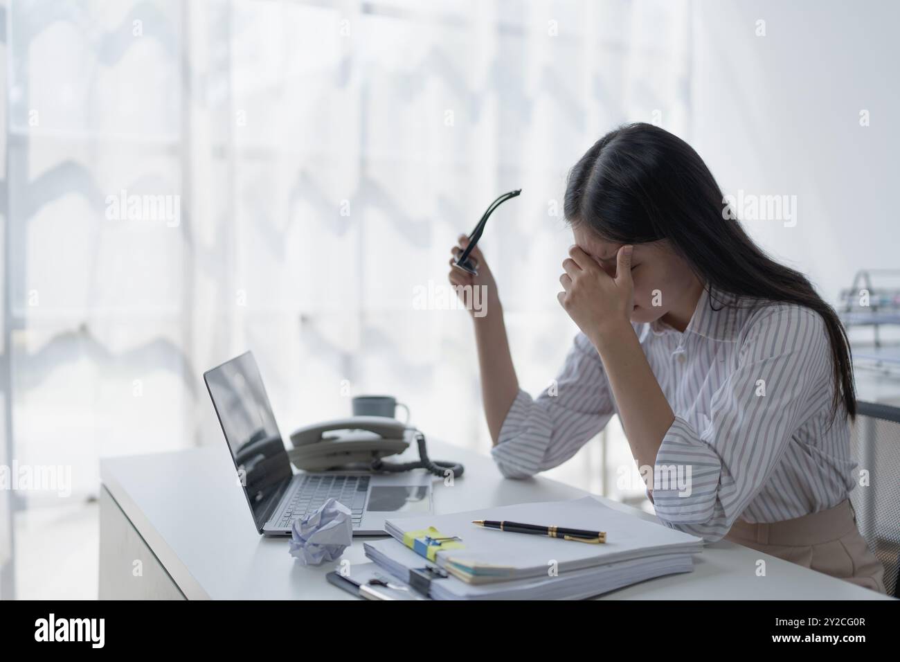 Geschäftsfrau plant eine Finanzprüfung, prüft Dokumente, während sie gegen das Burnout-Syndrom kämpft Stockfoto