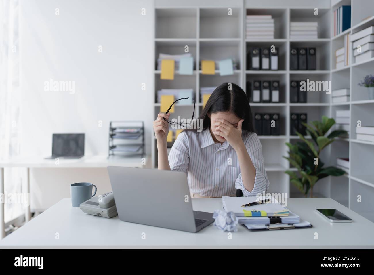 Geschäftsfrau plant eine Finanzprüfung, prüft Dokumente, während sie gegen das Burnout-Syndrom kämpft Stockfoto