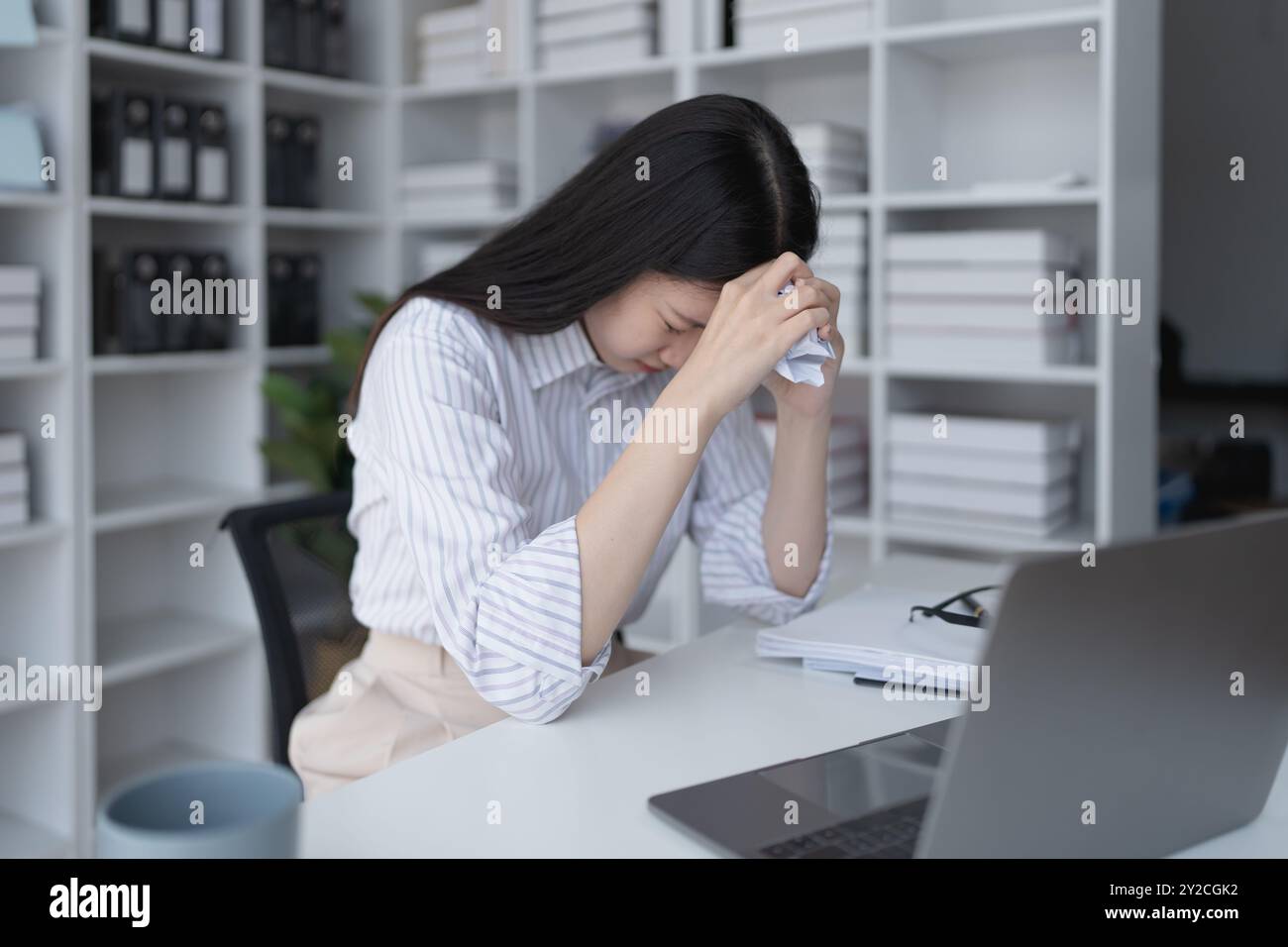 Geschäftsfrau plant eine Finanzprüfung, prüft Dokumente, während sie gegen das Burnout-Syndrom kämpft Stockfoto
