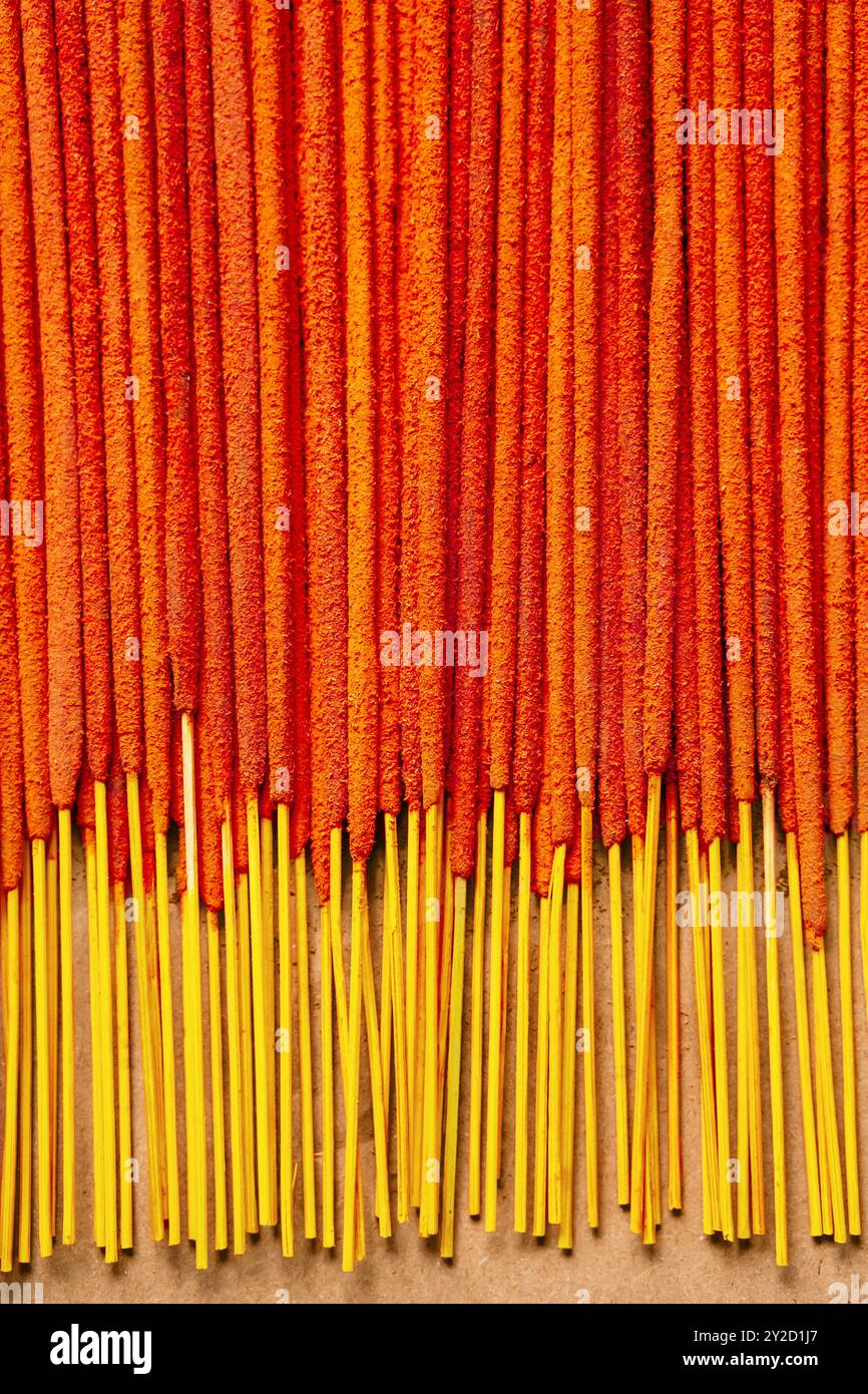 Orangene Räucherstäbchen sind ordentlich auf Papierhintergrund angeordnet. Entspannungs- und Spiritualitätskonzepte. Stockfoto