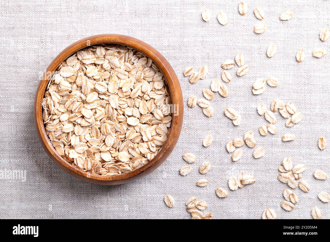 Haferflocken, Haferflocken in einer Holzschale auf Leinen. Geschälte und gedämpfte Hafergrieß zu Flocken gerollt und leicht geröstet. Stockfoto