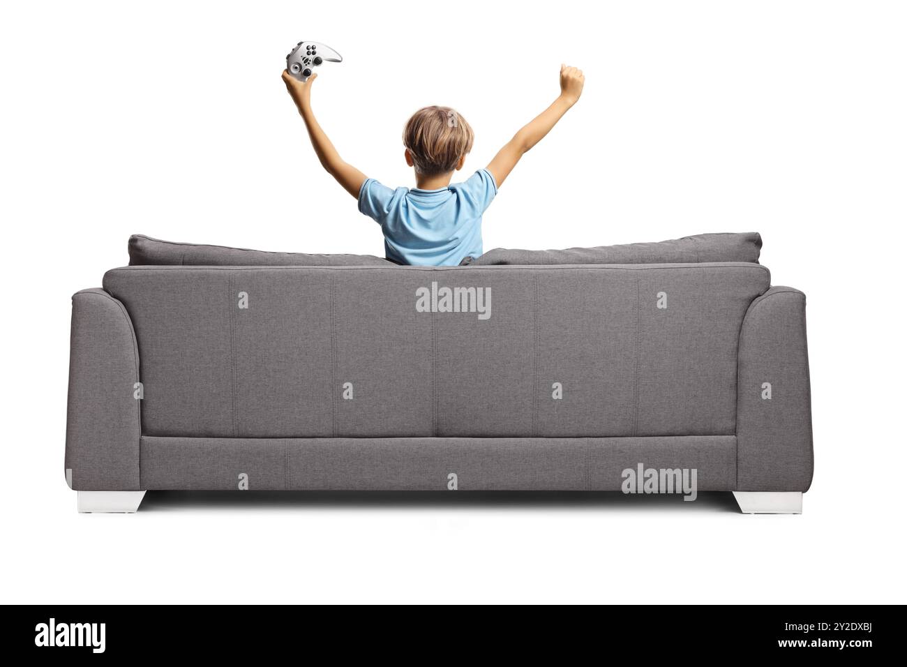 Rückansicht eines glücklichen Jungen, der auf einem Sofa mit einem Joystick für Videospiele sitzt, isoliert auf weißem Hintergrund Stockfoto