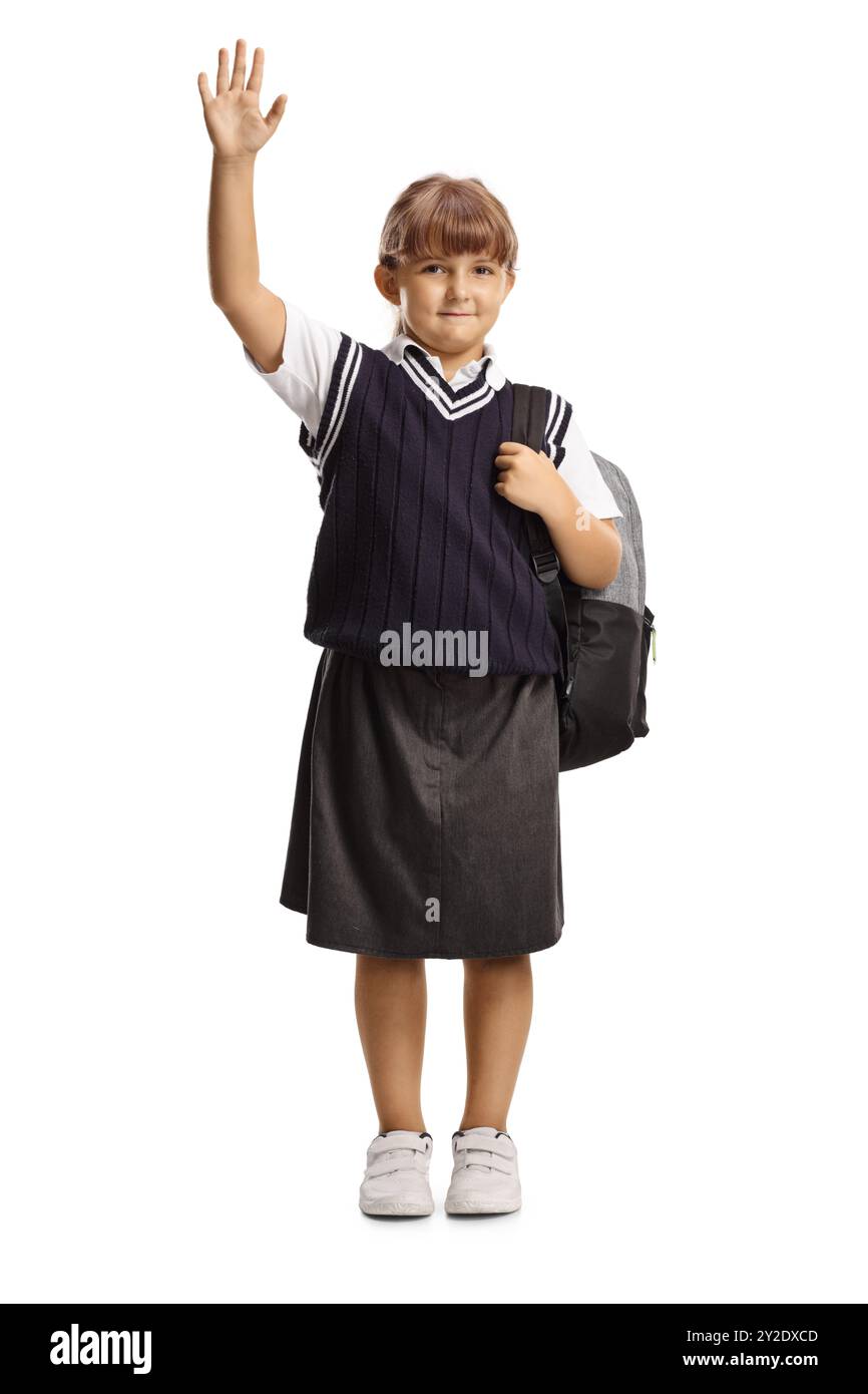 Schulmädchen in Uniform mit Rucksack und isoliert winkend auf weißem Hintergrund Stockfoto