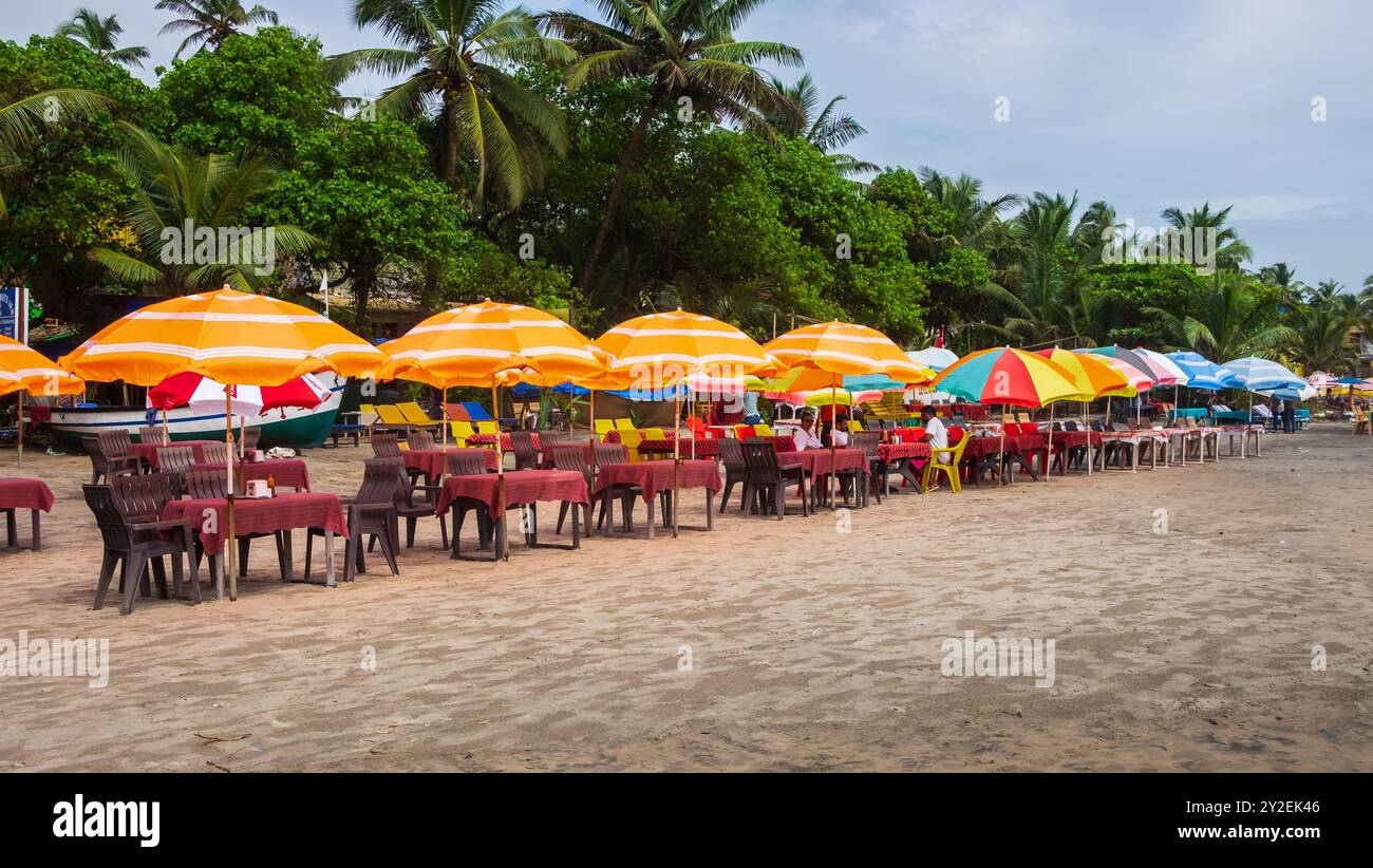 Blick auf den Strand von Arambol, North Goa. Arambol Strand mit Palmen, Sonnenschirme mit indischen und ausländischen Touristen. Nort Goa beliebte Touristenattraktion. Stockfoto