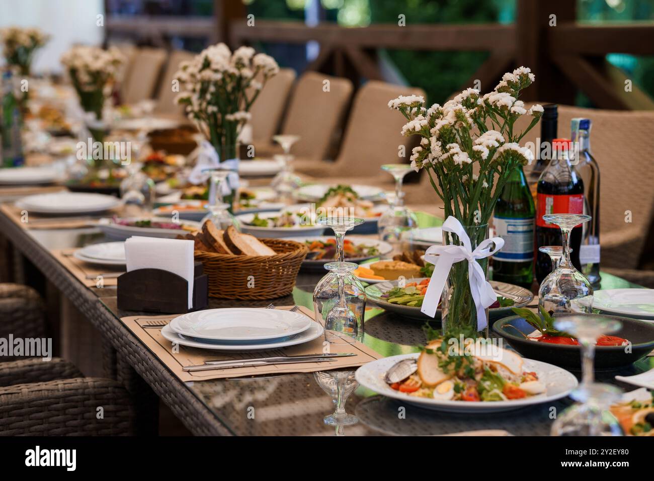 Elegantes Banketttisch-Set im Freien für festliche Zusammenkünfte mit Blumendekor und verschiedenen Gerichten. Stockfoto
