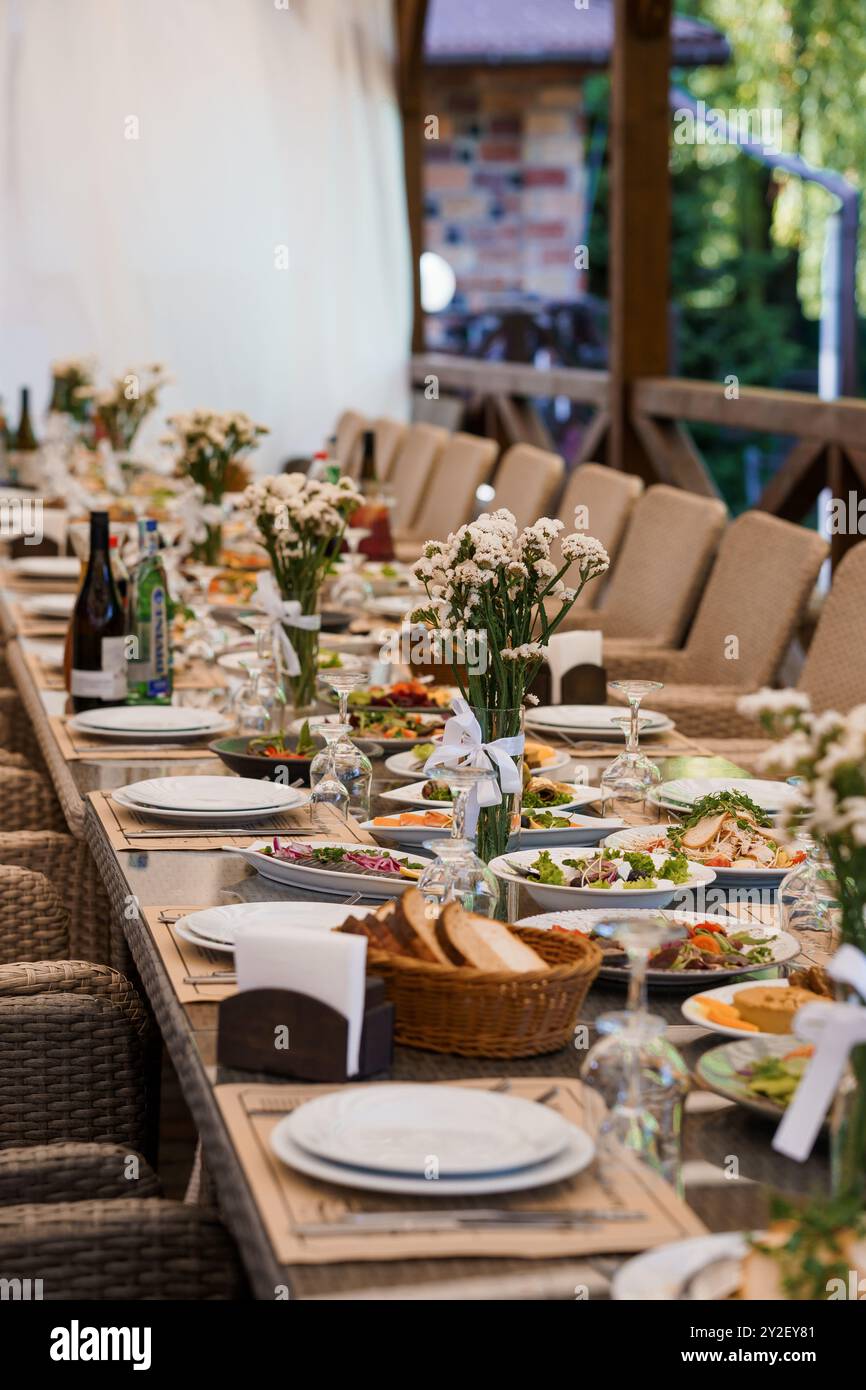 Elegantes Bankett im Freien mit Blumendekor und Gourmetgerichten in rustikaler Umgebung. Stockfoto