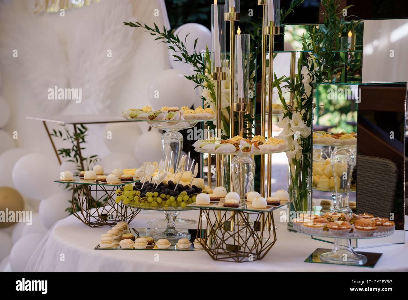 Eleganter Desserttisch mit elegantem Golddekor und delikaten Gebäckstücken für eine luxuriöse Veranstaltungsumgebung. Stockfoto